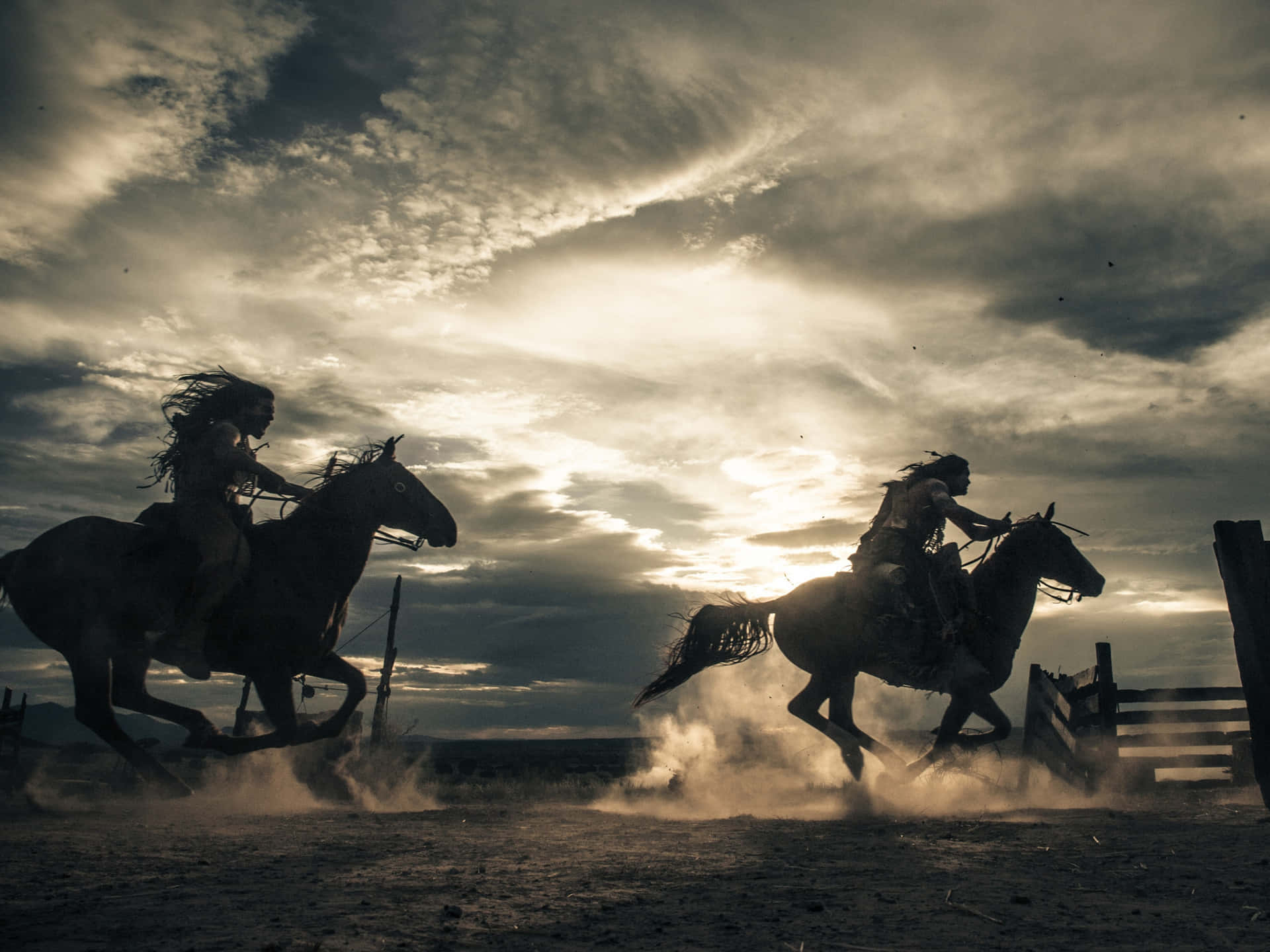 兩位騎馬者在日落時分奔馳在塵土飛揚的田野上。