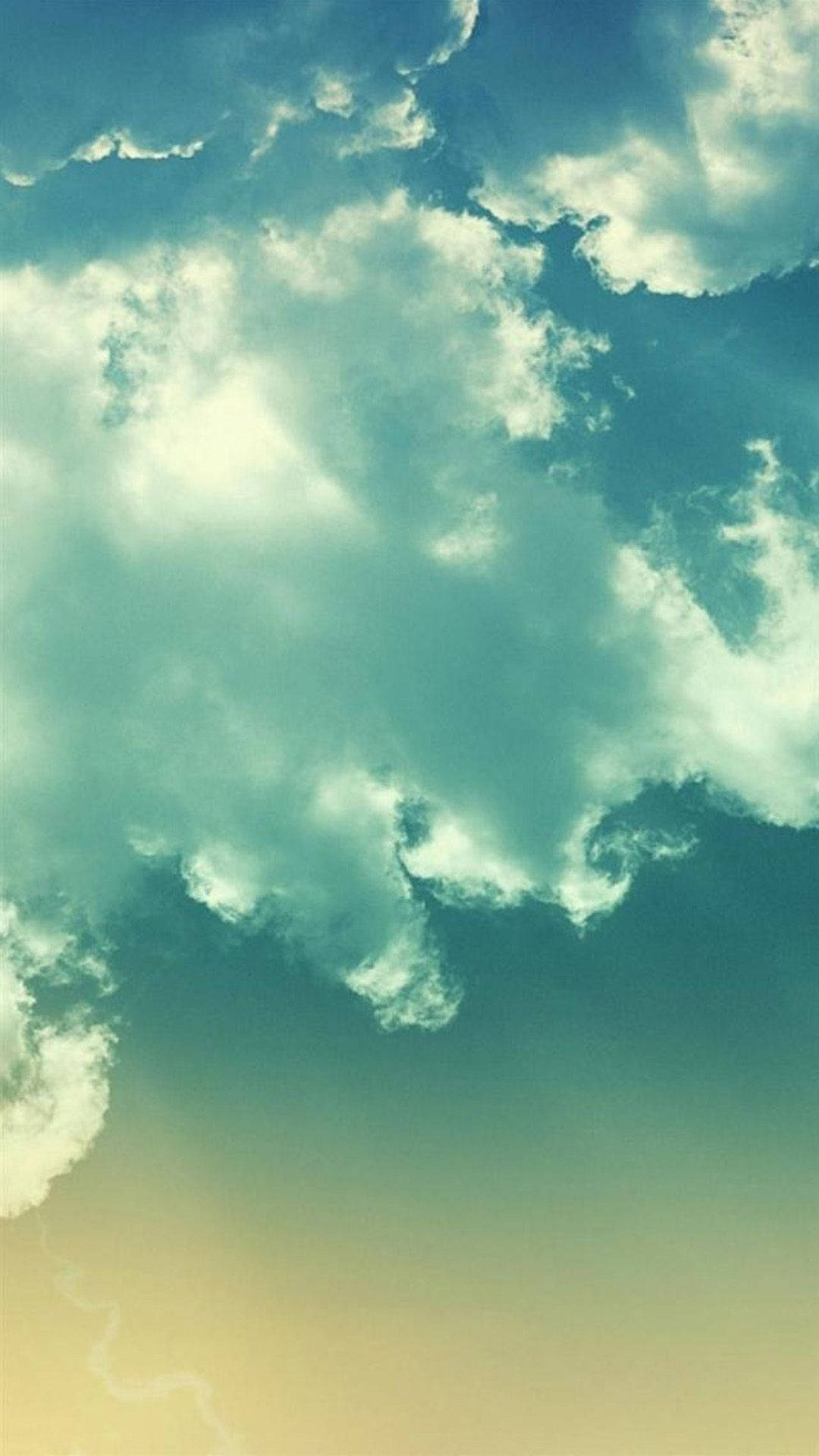 青綠色和奶油色的雲朵在漸變的日落天空中飄移。