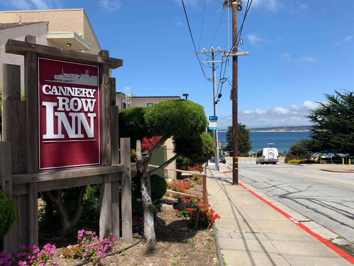 罐頭廠街旅館 壁紙 — Cannery Row Inn 的木製招牌矗立在開滿鮮花的人行道旁，在清澈的藍天下可欣賞海景。
