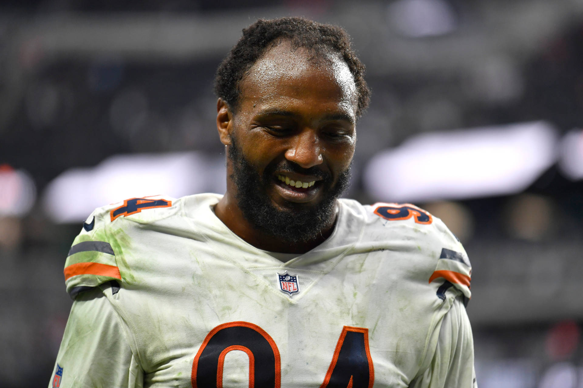 NFL球員94號在夜間穿著骯髒的白色球衣微笑。