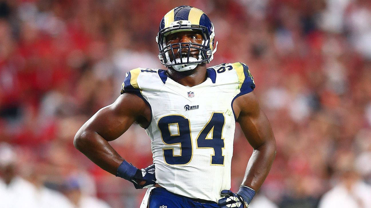 NFL美式足球運動員穿著公羊隊94號球衣，在夜間比賽中站在球場上。