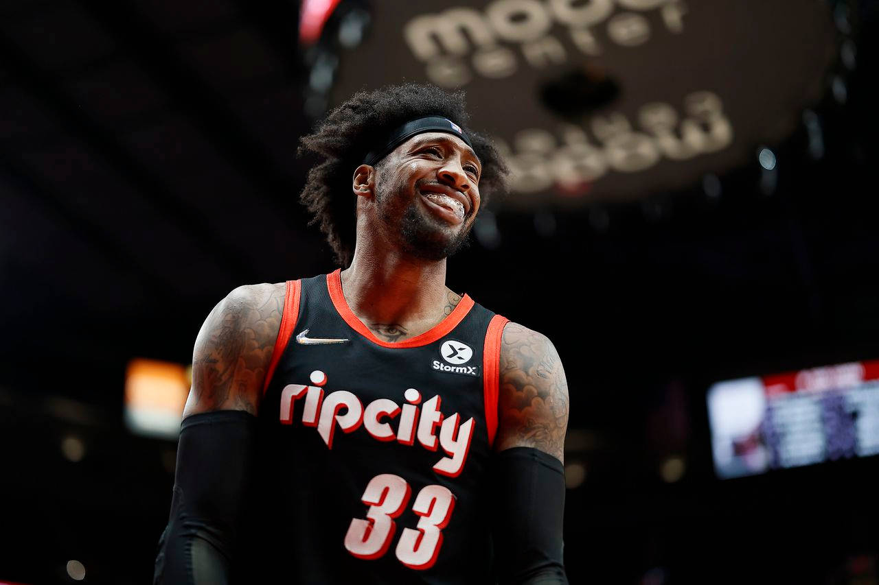 羅伯特·科維頓賽後真誠微笑 壁紙 — 一名身穿黑紅色 'Rip City' 球衣的籃球運動員在場館燈光下露出燦爛笑容，手臂上的紋身清晰可見。