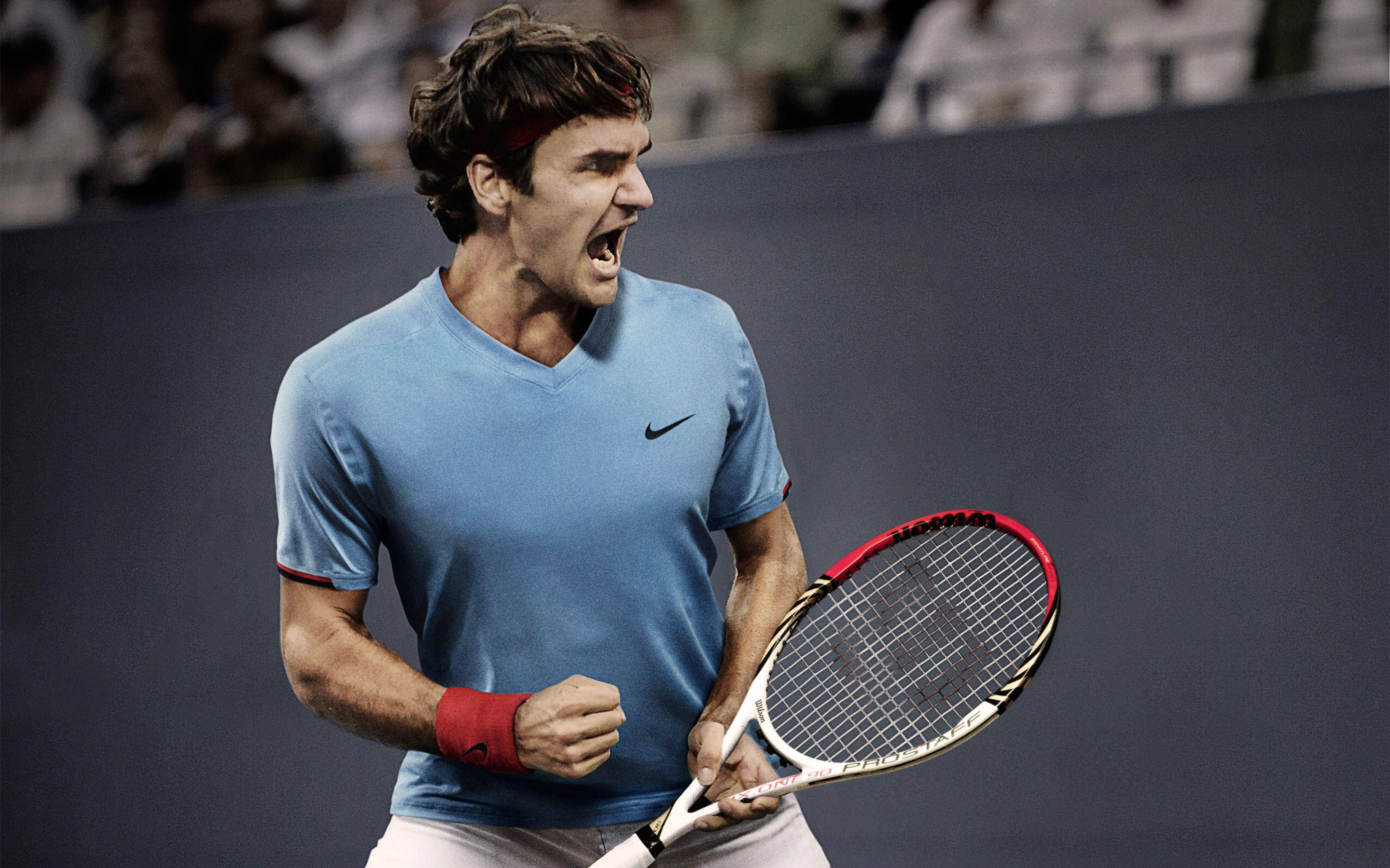 羅傑·費德勒網球耐克 壁紙 — 網球手在明亮的燈光下於硬地球場比賽中緊握球拍，發出勝利的咆哮。