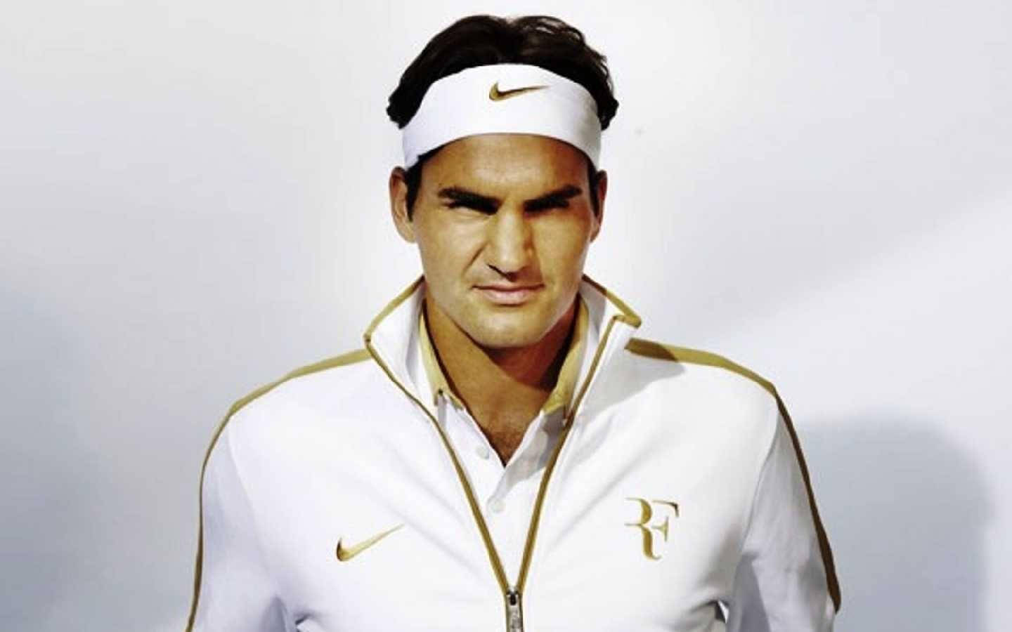 羅傑·費德勒耐克服裝標誌 壁紙 — 羅傑·費達拿身穿白色和金色Nike網球裝備，在簡單的攝影棚背景下凝視著。