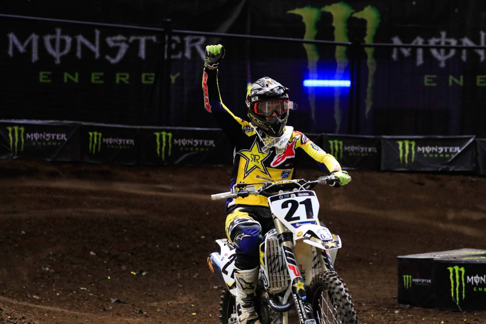 越野電單車手在夜間泥地賽道上，於Monster Energy燈光下高舉拳頭慶祝勝利。