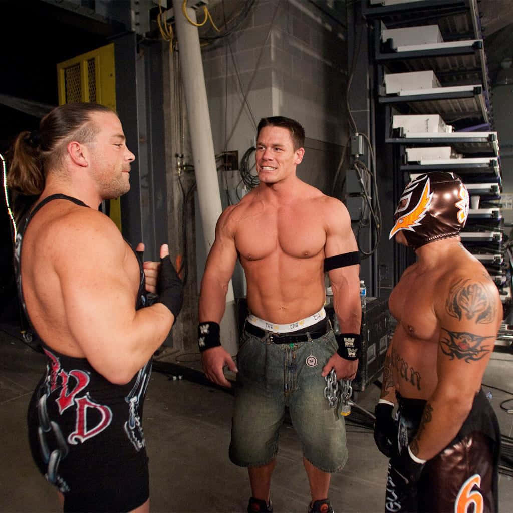 三位摔角手在後台區域，帶有紋身和裝備，互相對峙。 — WWE GIF 壁紙