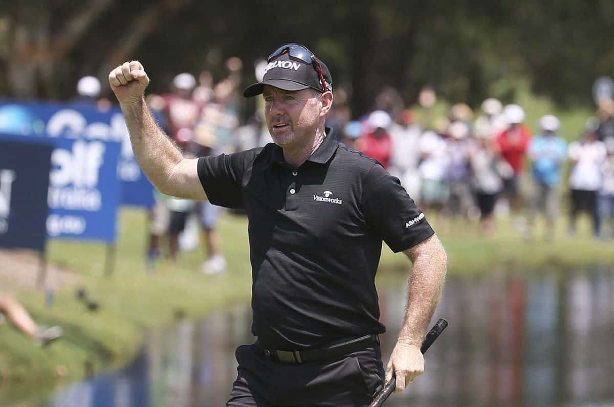 高爾夫球手在陽光普照、近水的高爾夫球場上舉起拳頭慶祝勝利。