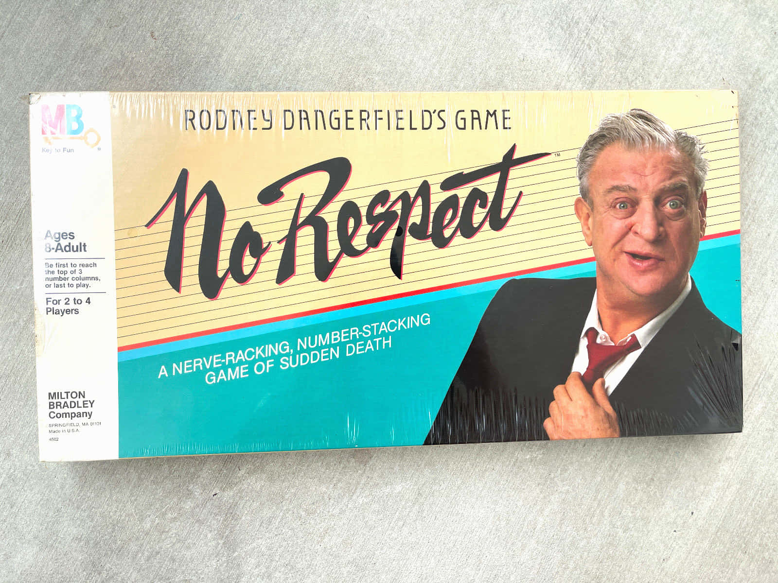 密封在灰色表面上的 Rodney Dangerfield 棋盤遊戲盒。