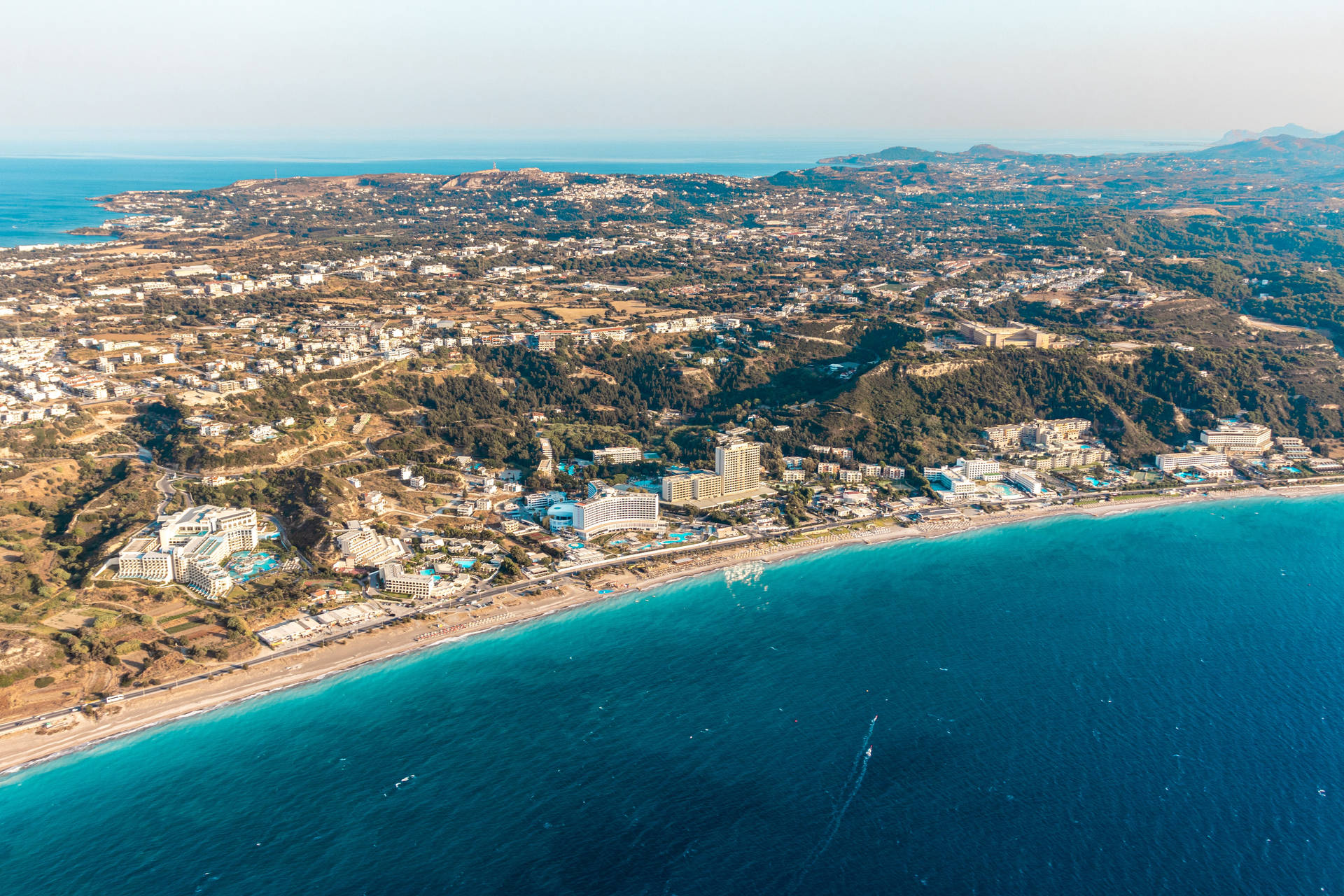 沿海小鎮，沿著碧綠的海水和綠色山丘有酒店和海灘。