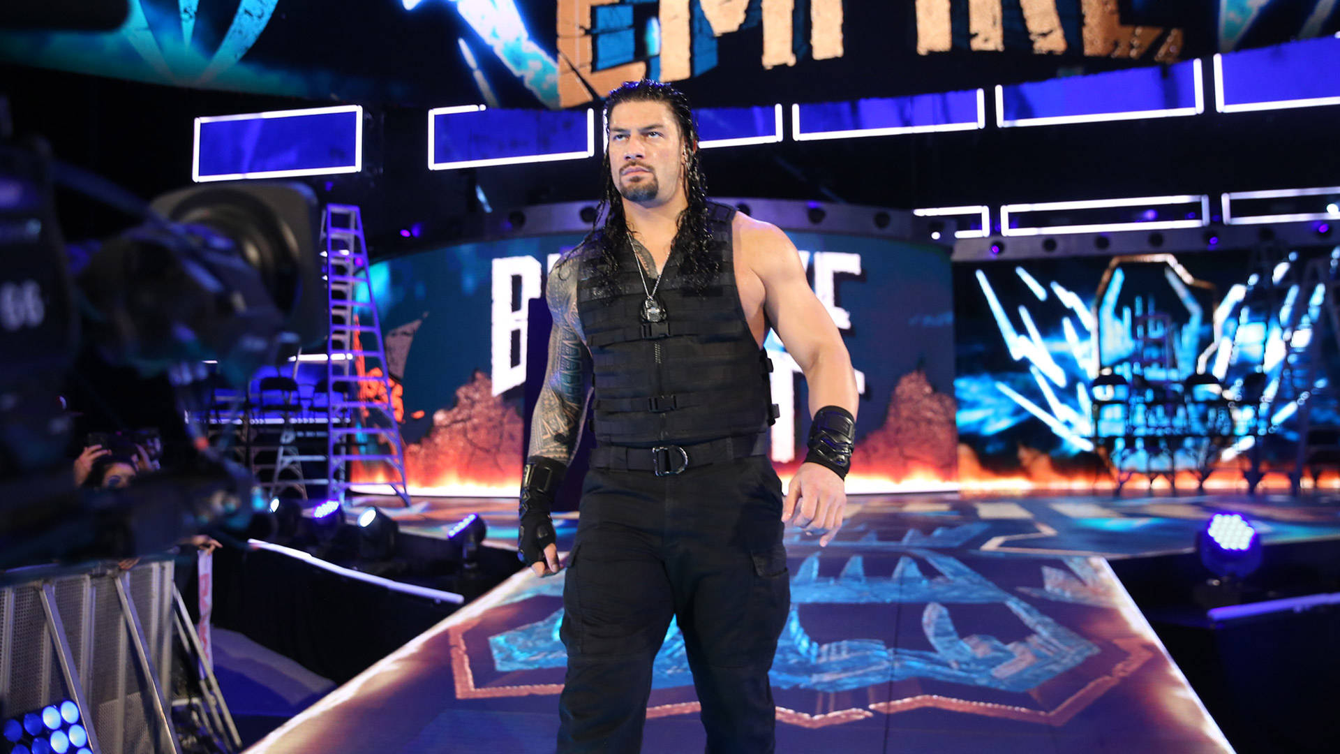 摔角手 Roman Reigns 在一個帶有相機和設備的明亮摔角舞台上。