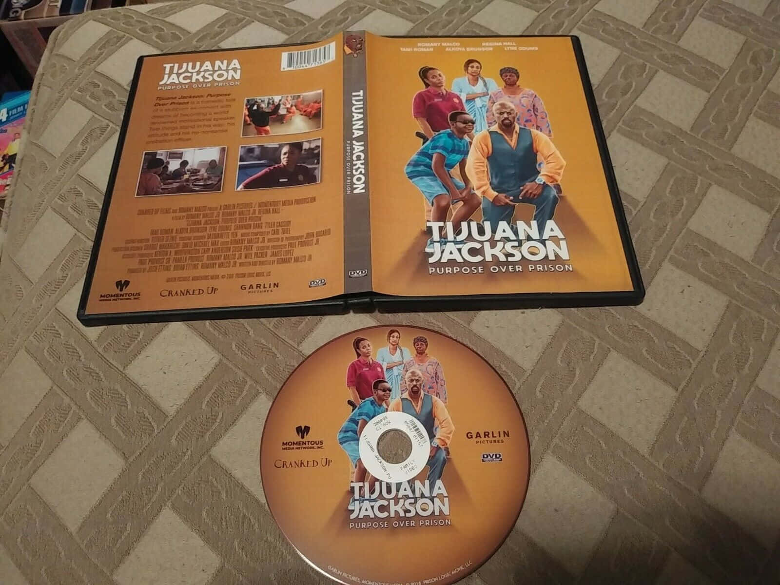 有圖案布料上的《Tijuana Jackson Purpose Over Prison》DVD盒和光碟。