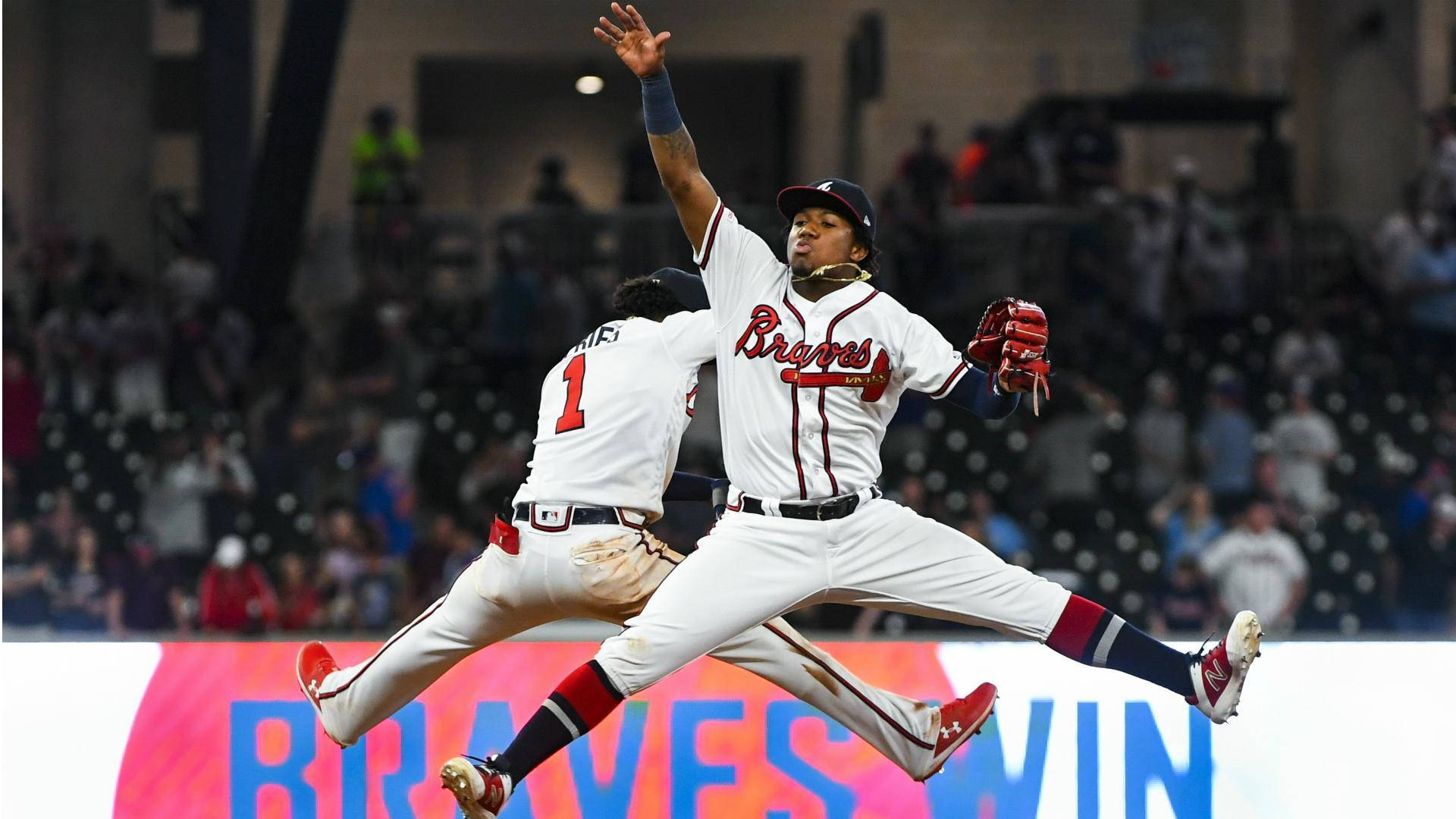 兩名棒球運動員在夜間比賽中跳躍慶祝，帶有「BRAVES WIN」標誌。