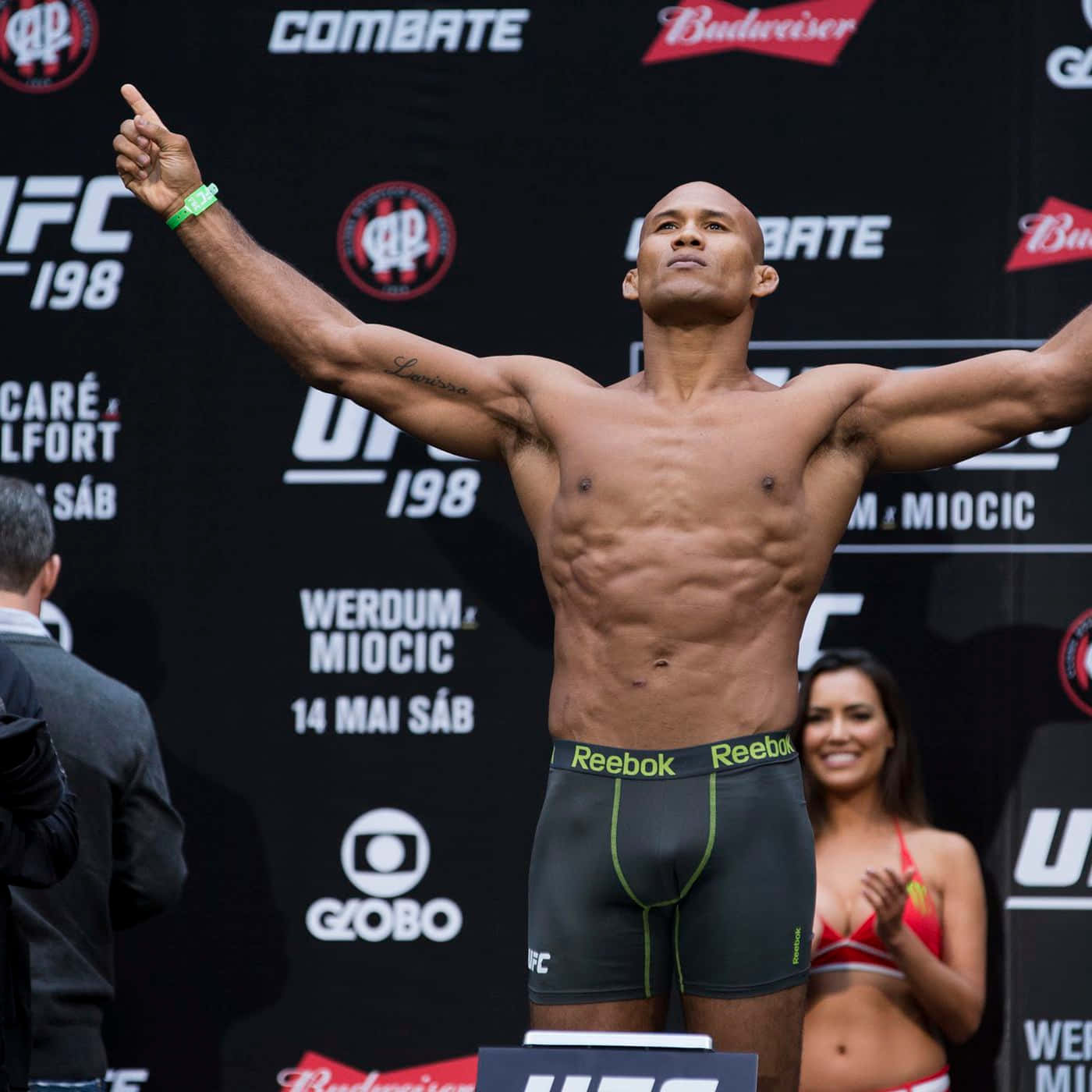 羅納爾多·蘇薩UFC 198稱重儀式 壁紙 — 一位肌肉發達的UFC拳手在稱重活動中高舉雙臂，勝利地站在體重秤上。