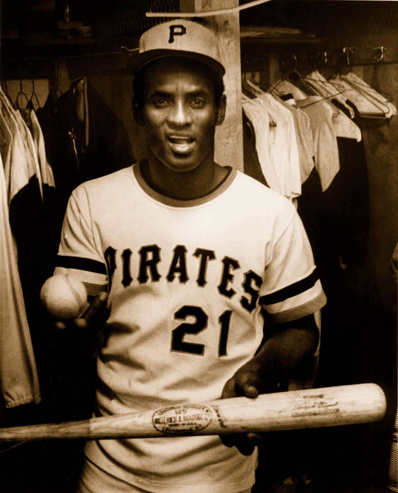 身穿 Pirates 球衣的棒球運動員在更衣室裡拿著球棒和球。