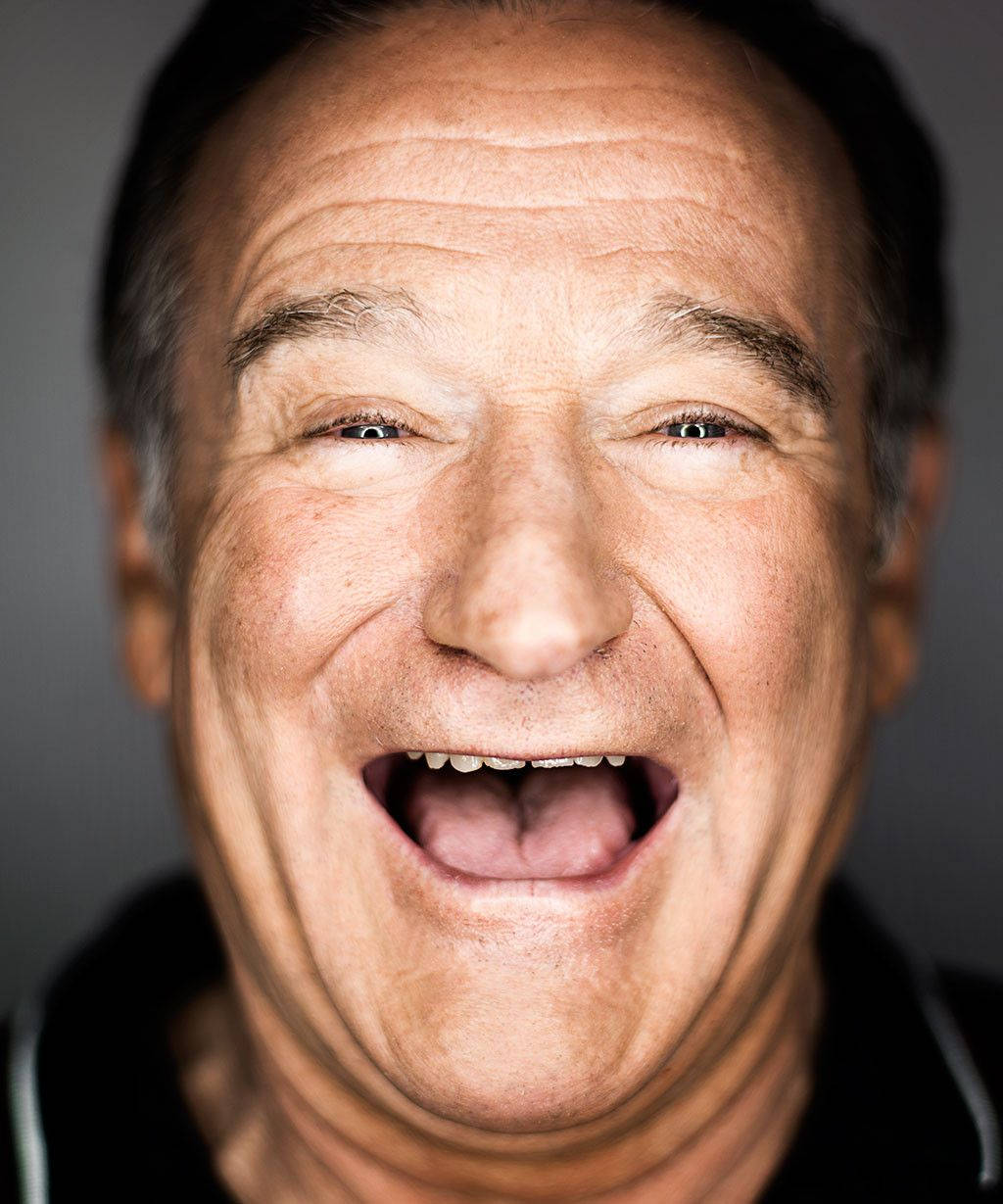 一名男子笑著，眼睛瞇起，嘴巴張開露出牙齒。