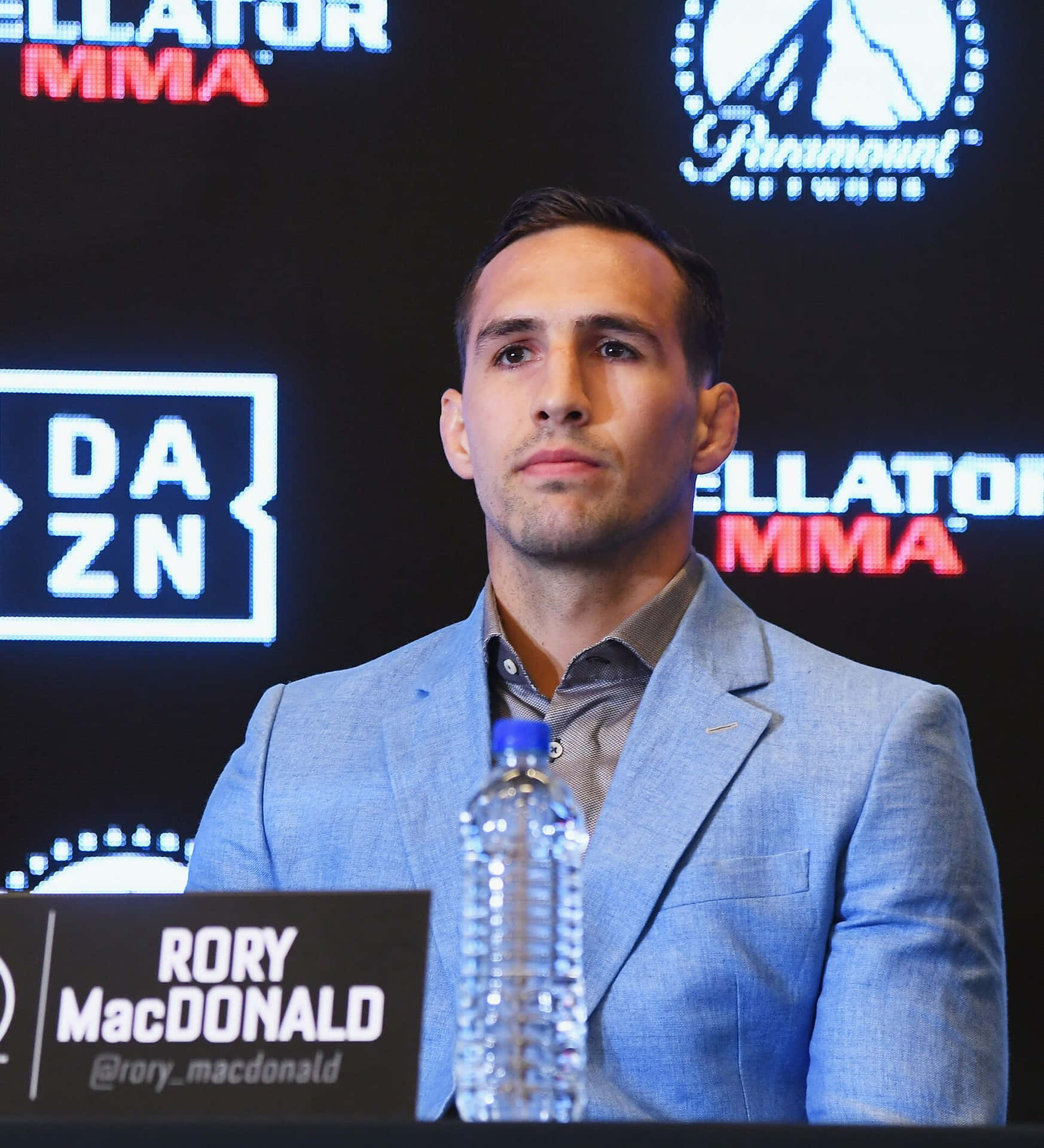 MMA 拳手 Rory MacDonald 在記者活動中，身後有贊助商標誌。