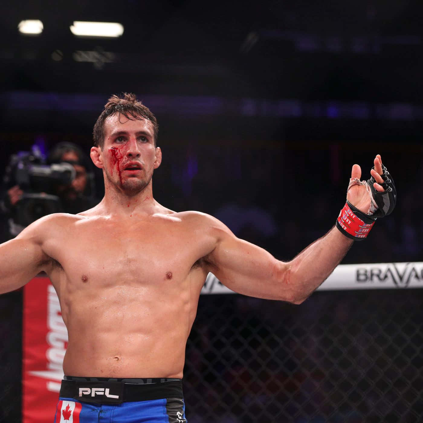 MMA拳手臉上帶血在八角籠中慶祝勝利。