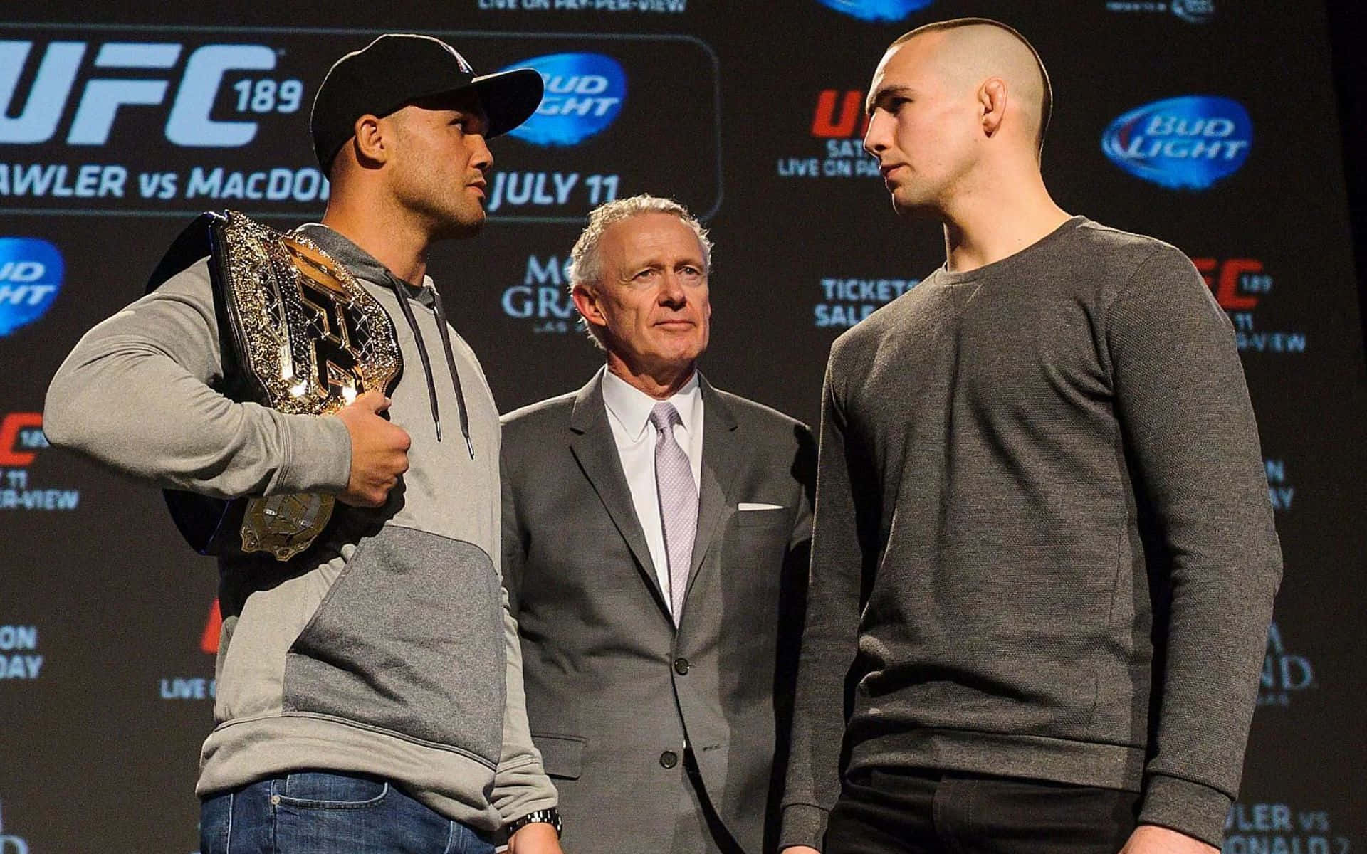 兩名男性UFC拳手在稱重活動中面對面站立，裁判站在他們之間。