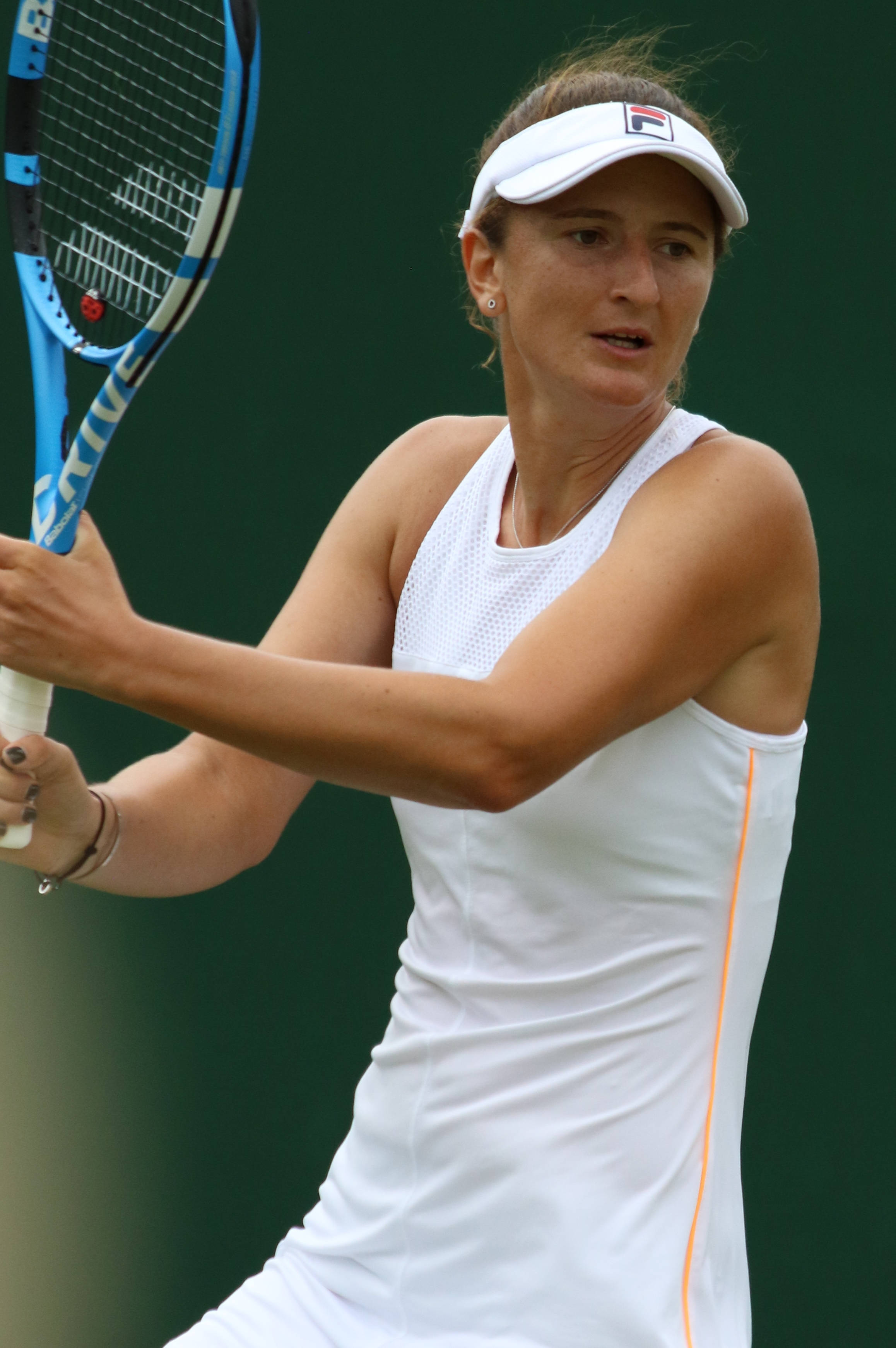 羅馬尼亞網球選手伊琳娜-卡梅利婭·貝古 壁紙 — 一位身穿白色運動服的女網球選手，在綠色背景下專注地揮動藍色球拍。