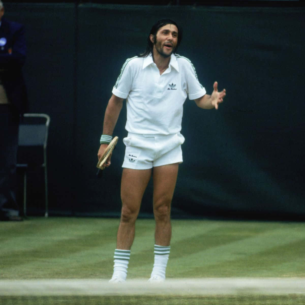 羅馬尼亞草地網球選手伊萊·納斯塔塞 壁紙 — 一位身穿全白Adidas裝備的復古網球選手，在明亮的日光下於草地場上生動地做手勢。