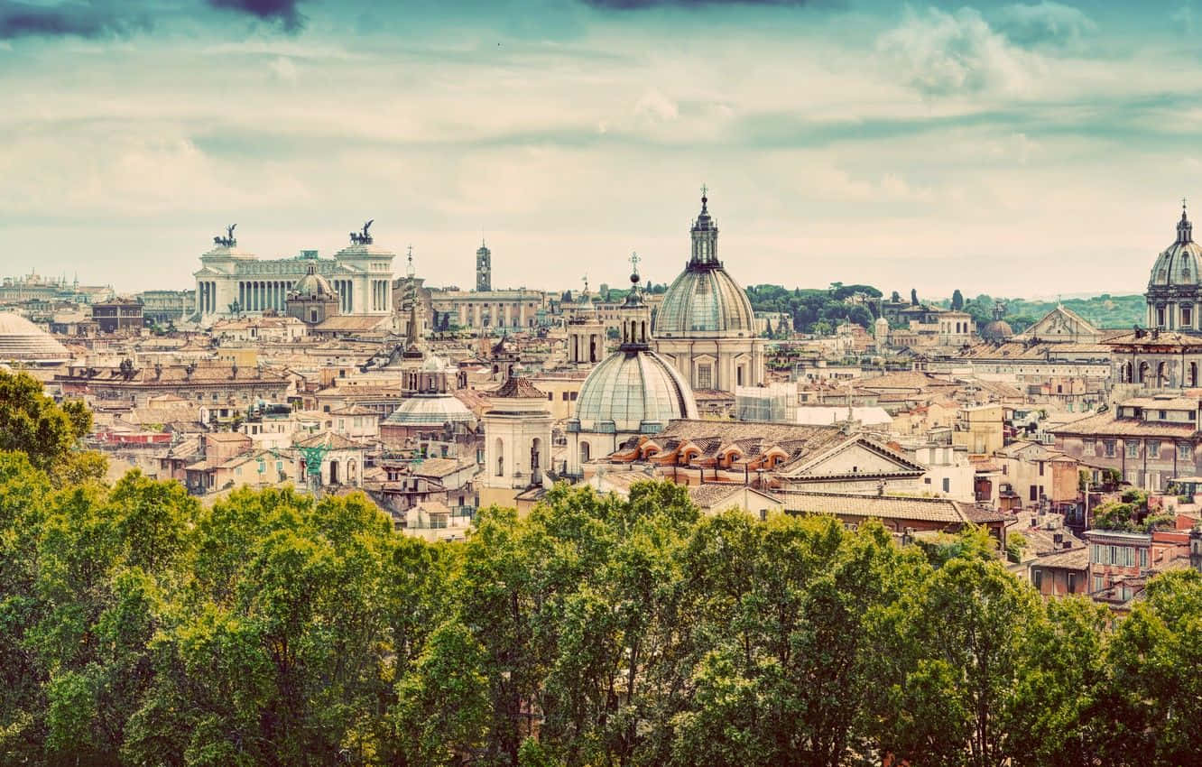 Rome 桌布 壁紙 — 羅馬歷史天際線的全景，圓頂教堂和古代遺跡在柔和的雲天下從茂密的綠樹中升起。