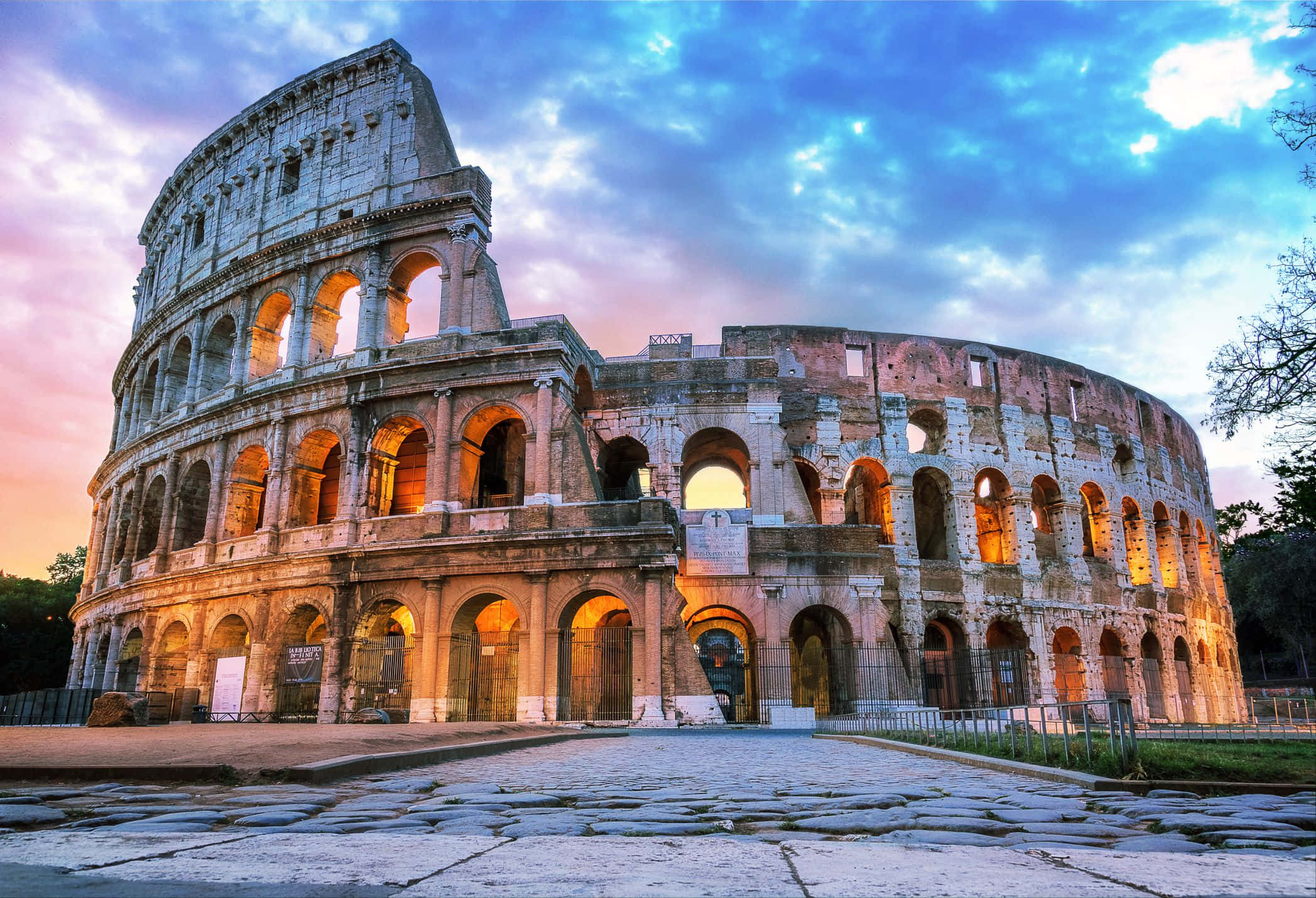 Roman 桌布 壁紙 — 羅馬的古代競技場在戲劇性的黃昏天空下，帶着粉紅色和藍色的雲彩，溫暖地發光。