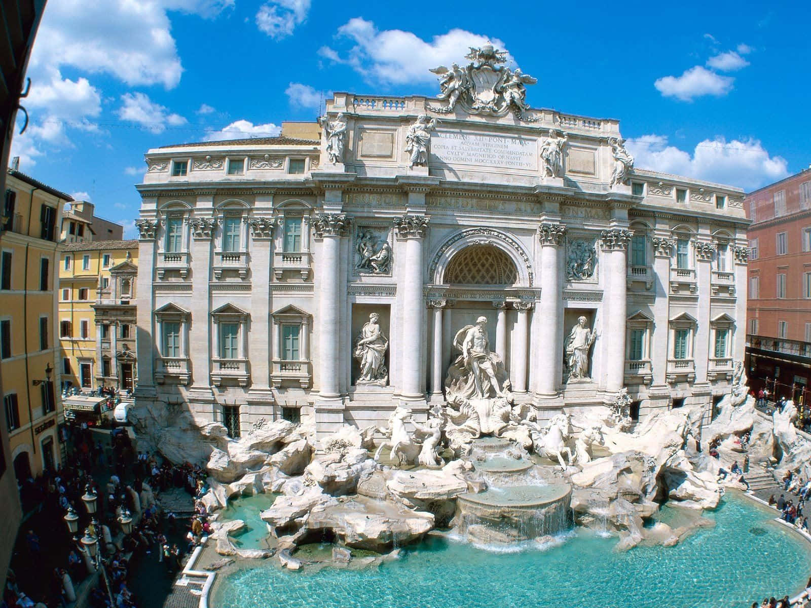 Rome 桌布 壁紙 — 羅馬的特雷維噴泉在明亮的藍天白雲下閃耀，遊客聚集在其華麗的巴洛克雕塑和碧綠色的水周圍。