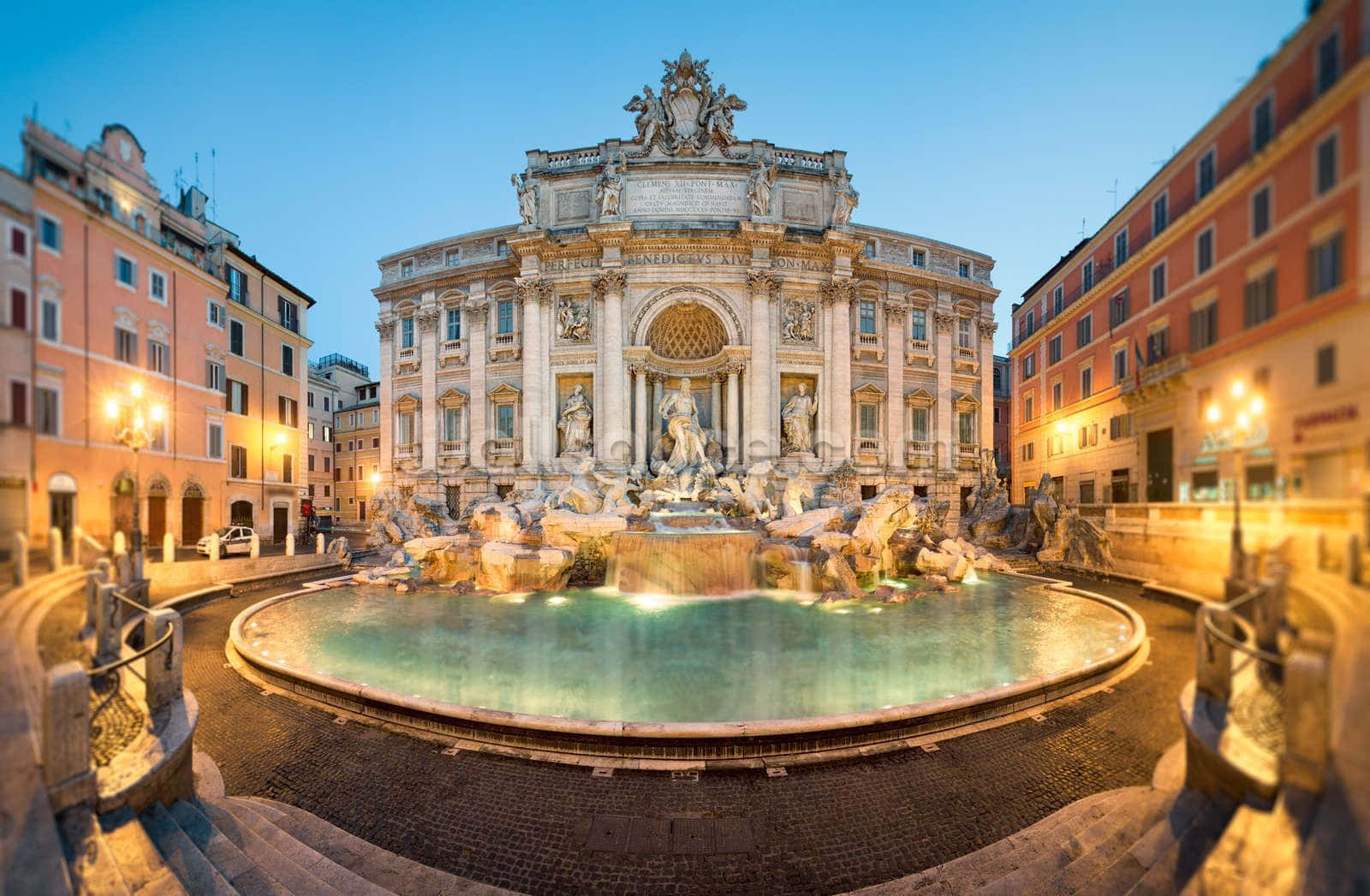 Rome 桌布 壁紙 — 羅馬的許願池在暮色燈光下閃耀，水流從大理石雕塑中傾瀉而下，周圍是溫暖燈光照亮的建築。