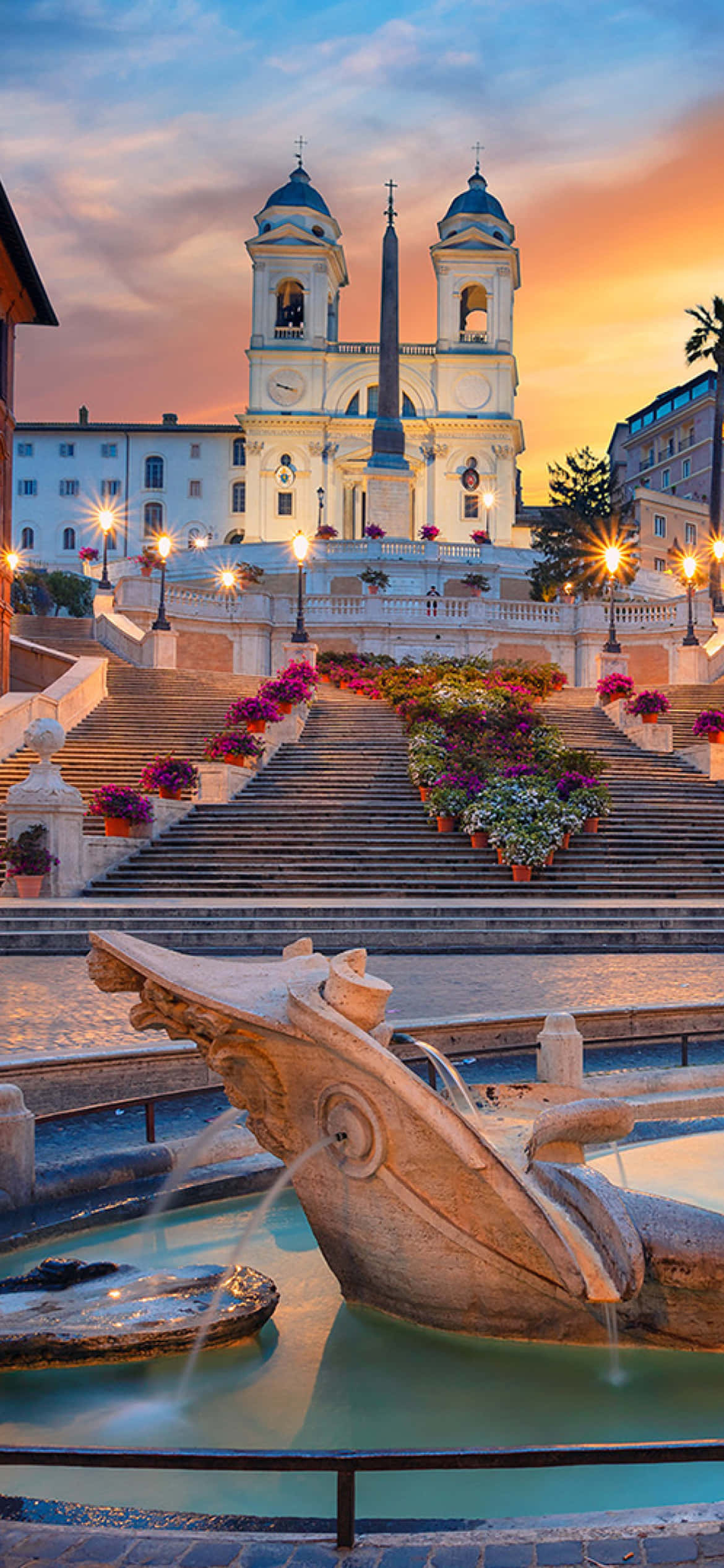 羅馬西班牙階梯日落美景 壁紙 — 夕陽將西班牙階梯和聖三一教堂沐浴在溫暖的光線中，噴泉和花盆點綴著宏偉的階梯。