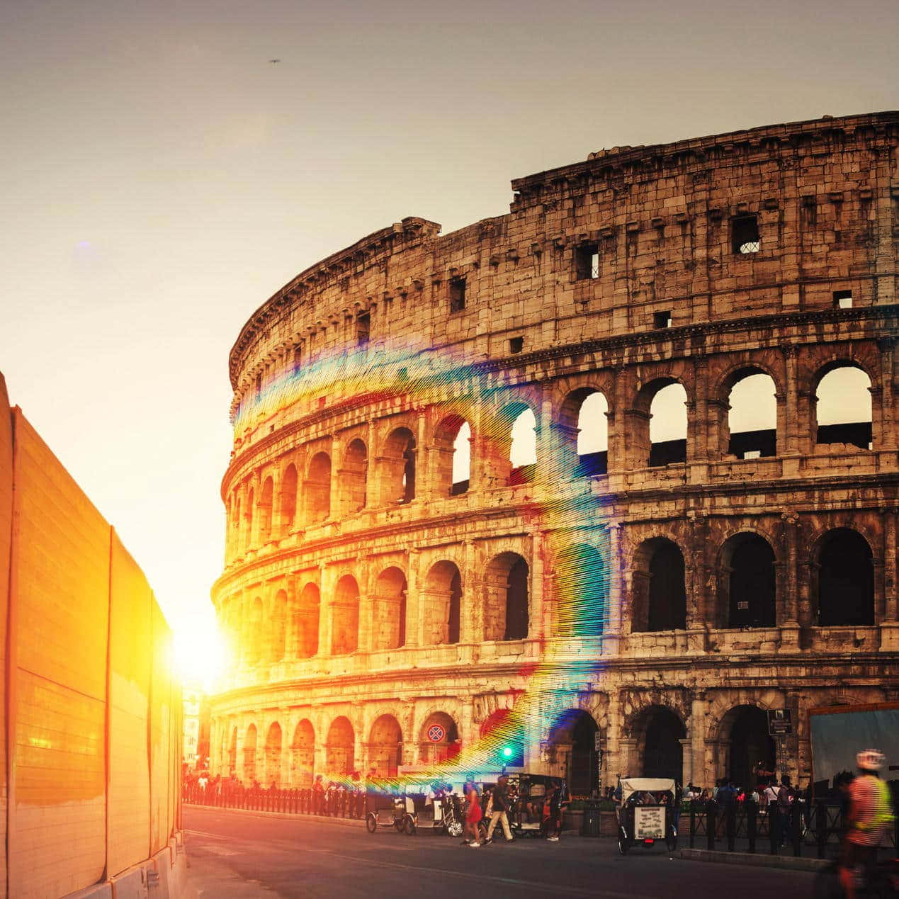 Roman 桌布 壁紙 — 羅馬鬥獸場沐浴在金色夕陽中，一道鮮豔的彩虹鏡頭光暈劃過其古老的石拱門。