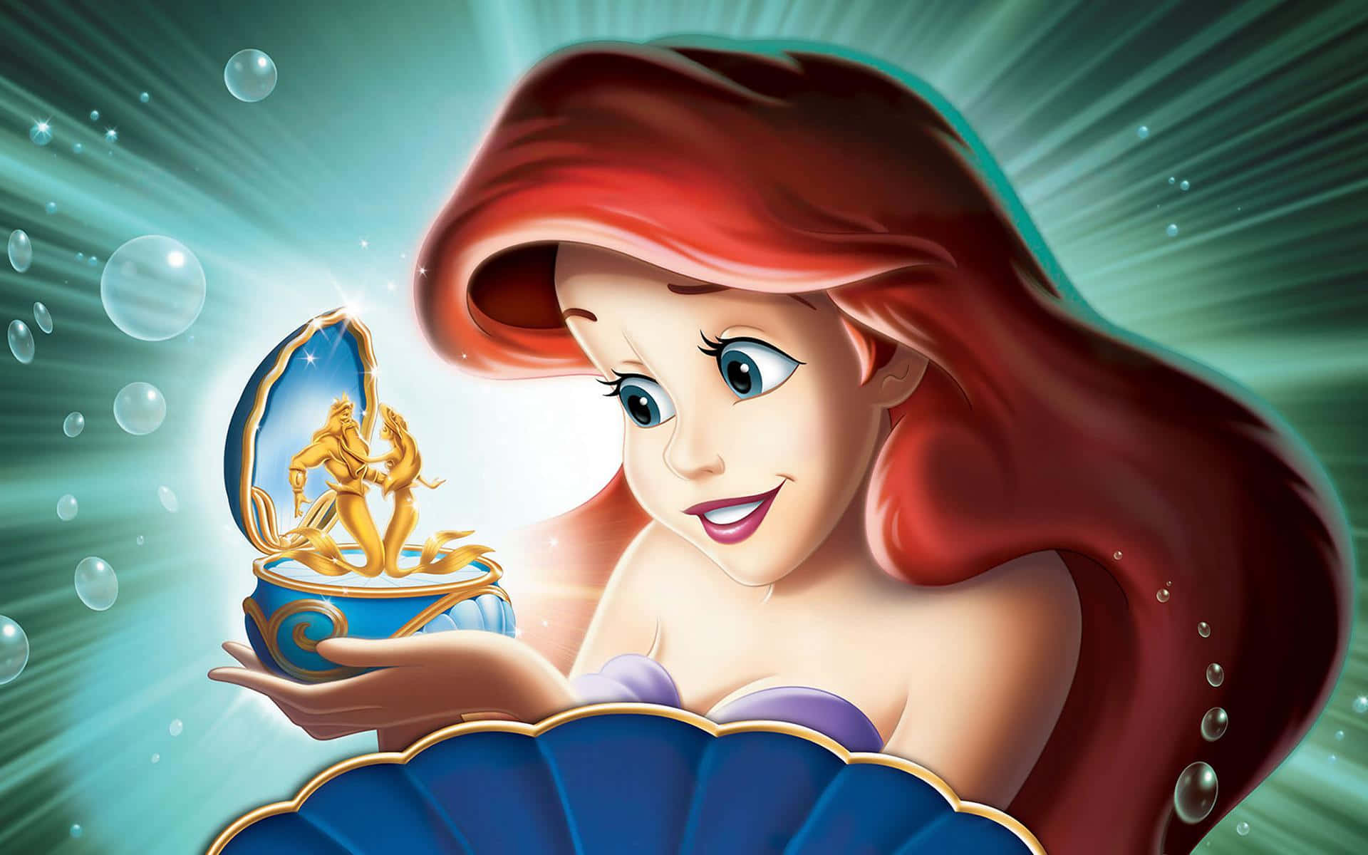 Kawaii Mermaid 桌布 壁紙 — 美人魚艾莉爾微笑著，在水下抱著一個發光的貝殼寶箱，裡面有一個金色雕像。