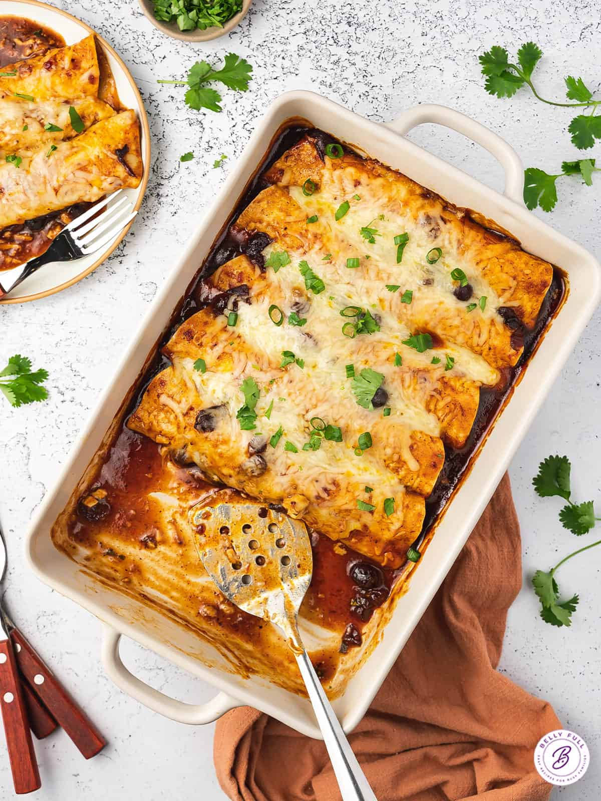 美味 enchiladas 卷 壁紙 — 金黃色芝士玉米捲餅放在白色烤盤中，飾以新鮮芫荽和黑豆。
