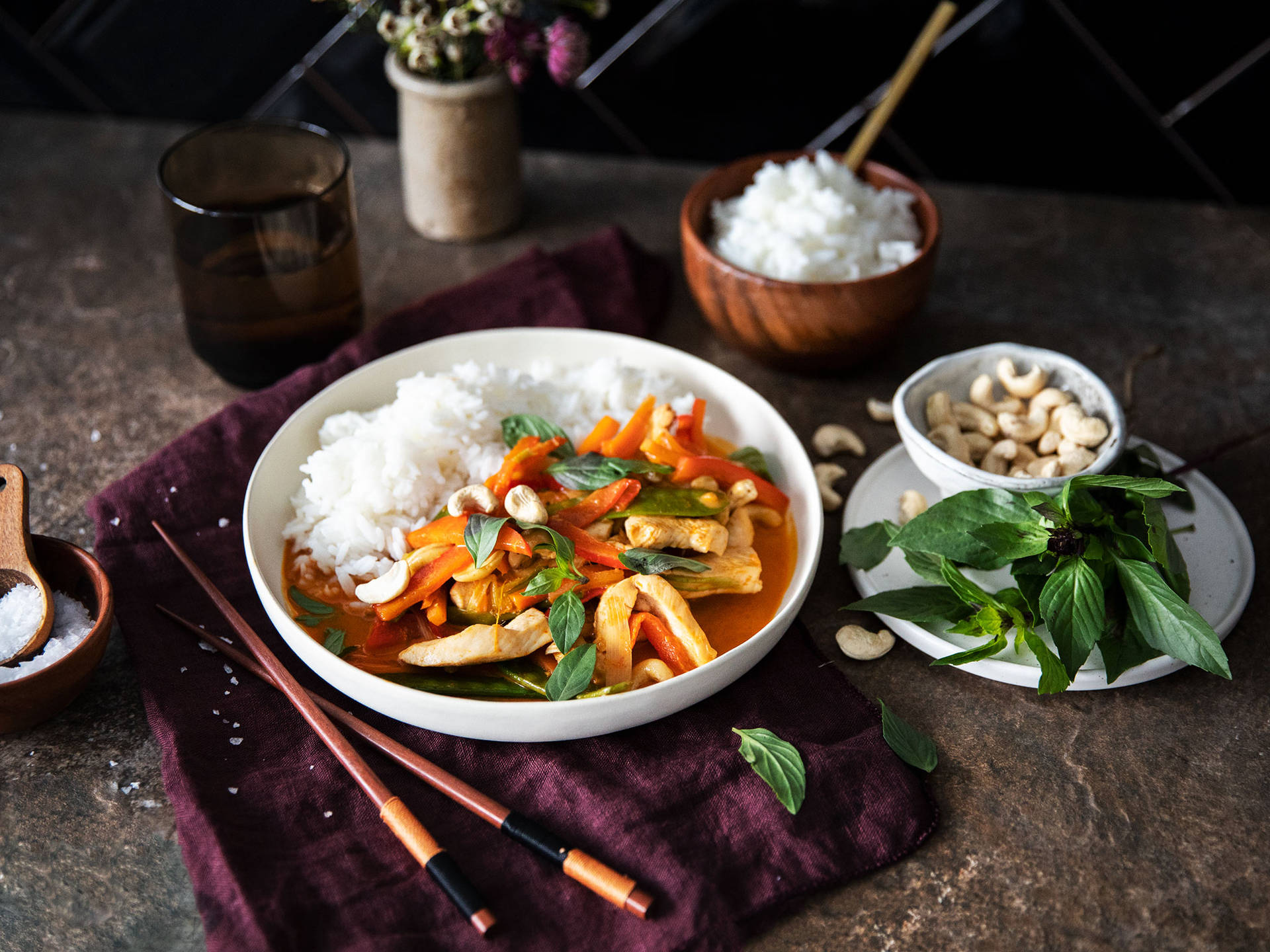 泰式雞肉咖喱配米飯和新鮮羅勒，置於深色桌上。