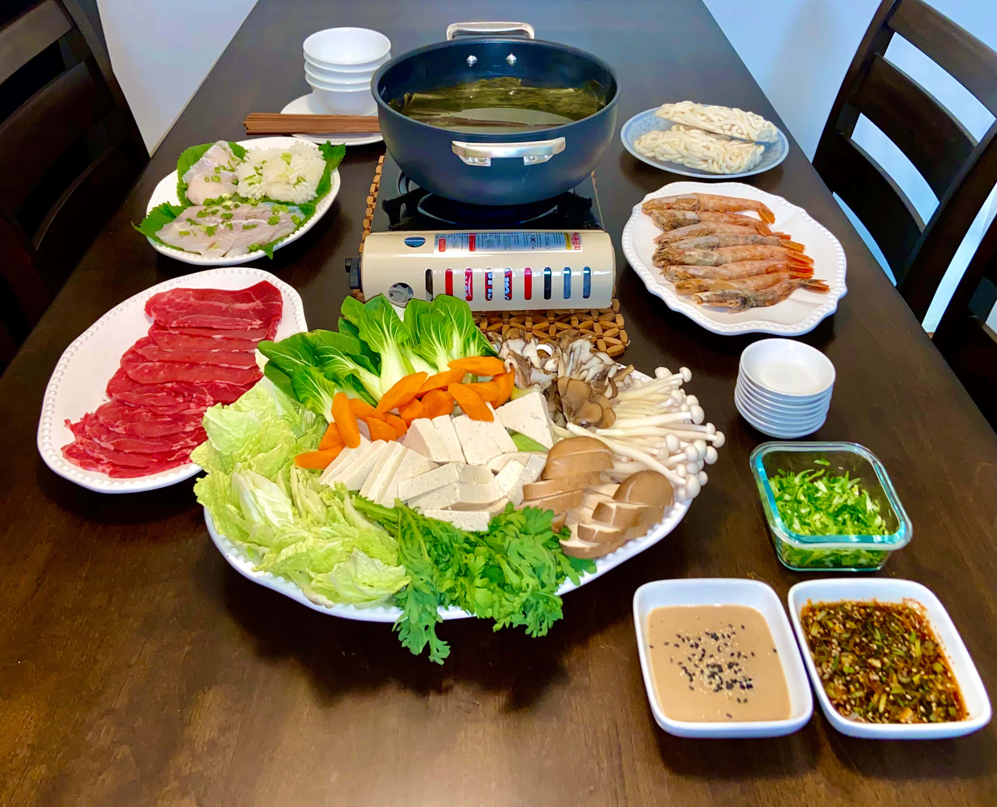 美味涮涮鍋體驗 壁紙 — 一張木桌上擺滿了色彩繽紛的火鍋食材，包括切片牛肉、蝦、蘑菇和新鮮蔬菜。