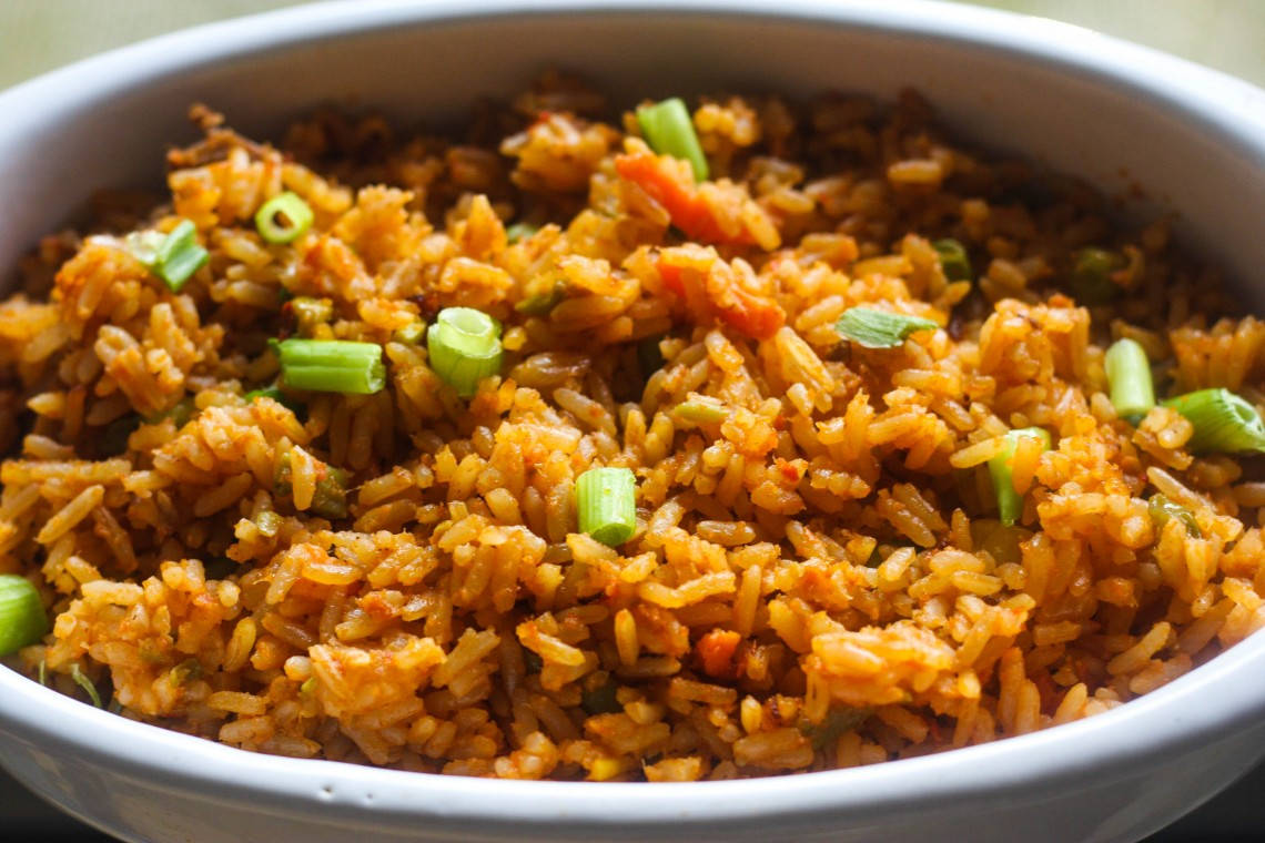 美味的約洛夫飯 壁紙 — 一個白色碗中充滿活力的橙色炒飯配青蔥的特寫。