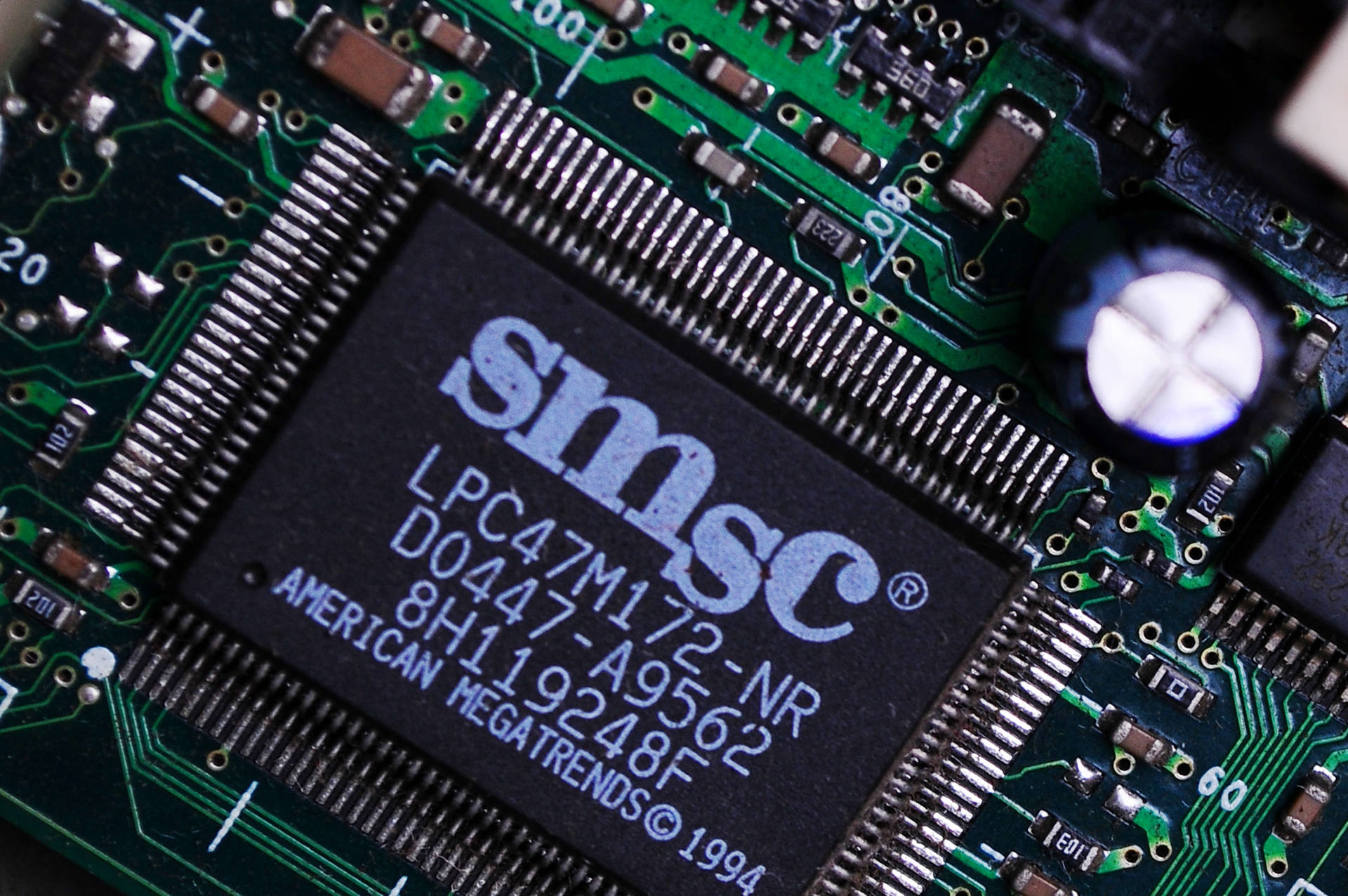 綠色電路板特寫，帶有SMSC微晶片和周圍的電子元件。