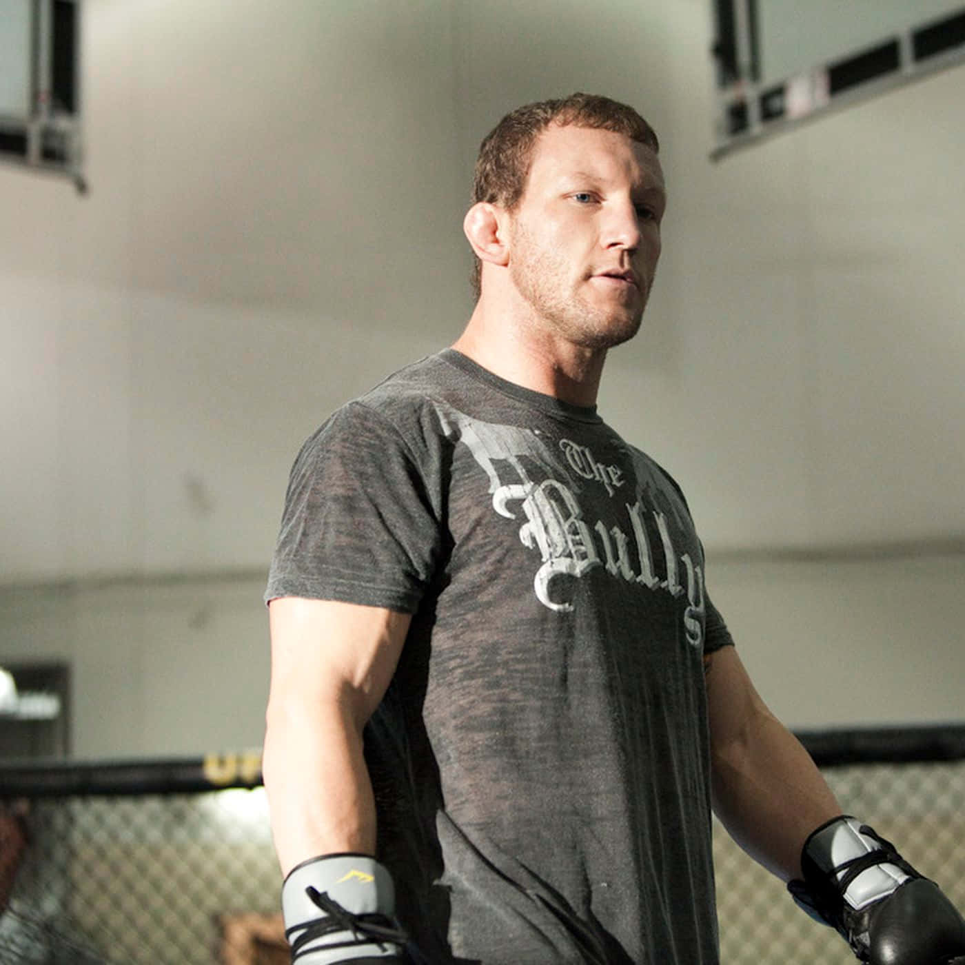 美國MMA選手格雷·梅納德 壁紙 — 一個肌肉發達的男人穿著灰色 'The Bully' T恤和拳擊手套，帶著專注的強度站在UFC八角籠內。