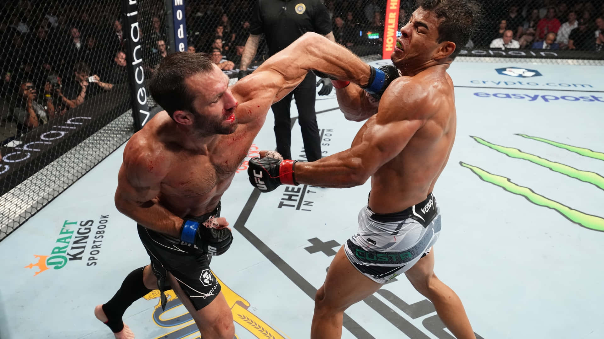 美國UFC選手盧克·羅克霍德與巴西選手保羅·科斯塔 壁紙 — 兩名肌肉發達的拳手在UFC八角籠中激烈交鋒，滿臉鮮血，表情猙獰，在明亮的場館燈光下。
