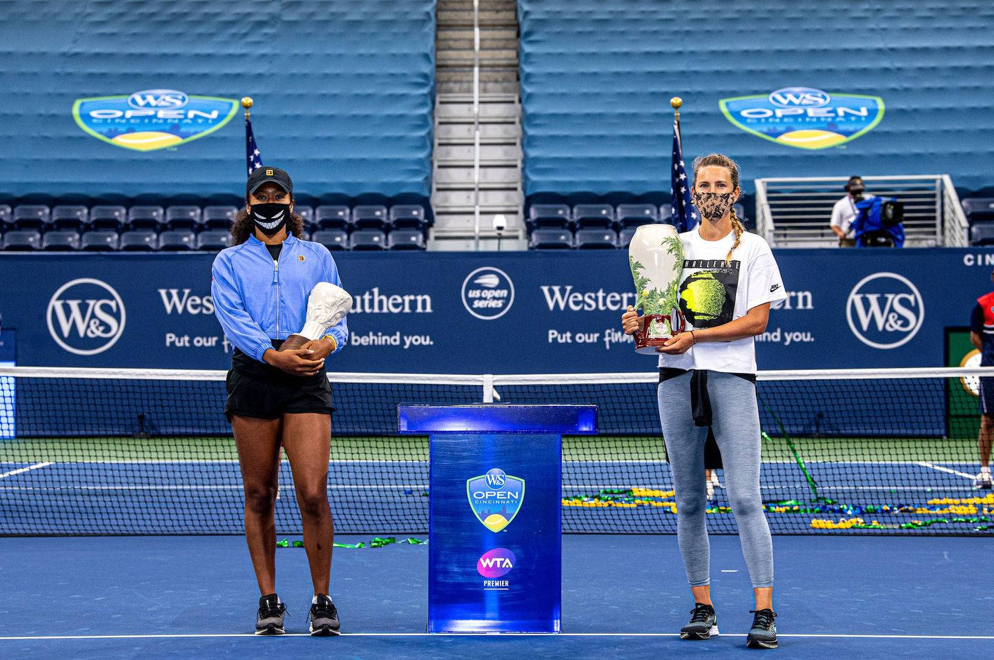 美國公開賽選手捧獎盃 壁紙 — 兩位女子網球選手在WTA賽事頒獎典禮上，站在藍色硬地球場上手持獎盃。