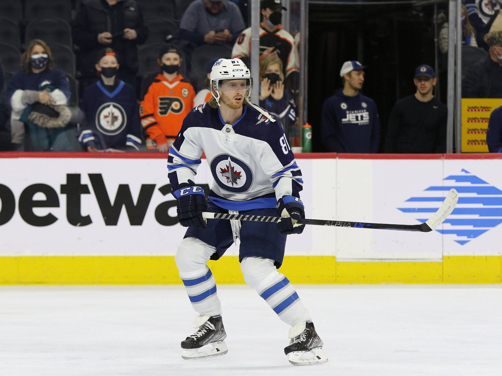 美國冰球運動員凱爾·康納於NHL賽季精彩瞬間 壁紙 — 一名身穿藍白裝備的溫尼伯噴射機冰球球員在冰上激烈滑行，背景有觀眾。