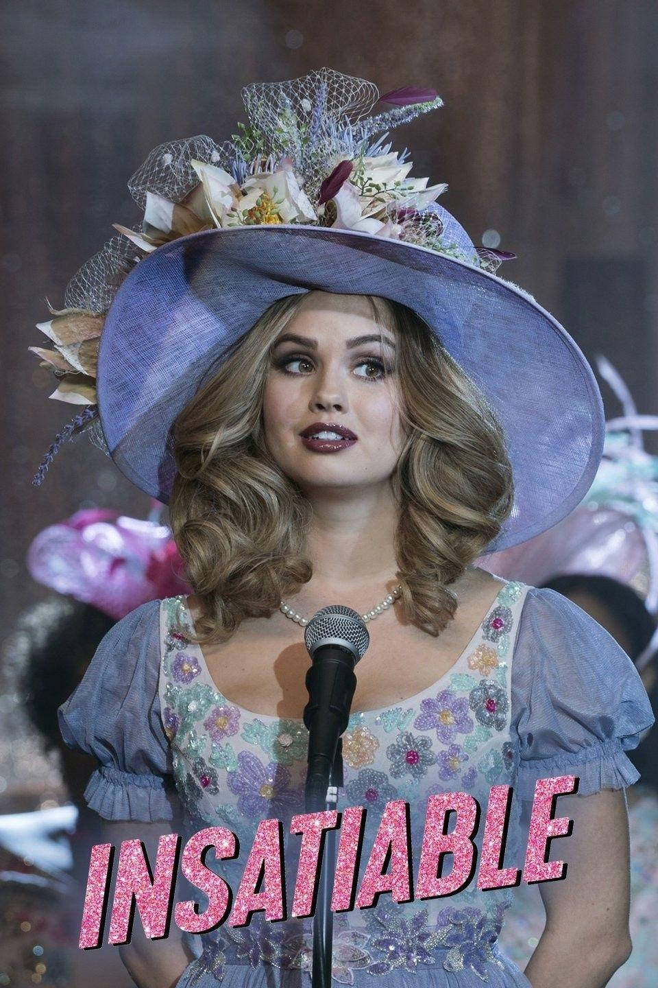 美國喜劇劇集《Insatiable》 壁紙 — 一位戴著華麗裝飾的紫色帽子和花卉連衣裙的女性站在麥克風前，上面有閃閃發光的粉紅色「INSATIABLE」標題疊加。