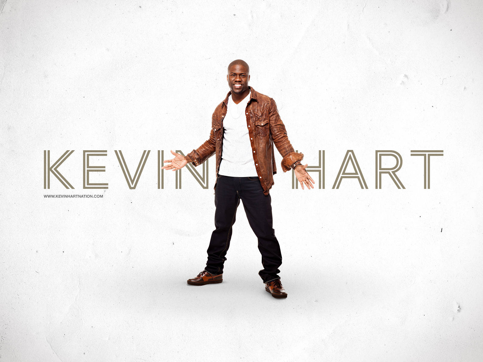 美國喜劇演員凱文·哈特 壁紙 — Kevin Hart 穿著棕色皮外套，在帶有紋理的白色背景上微笑，他的名字以大字母顯示。