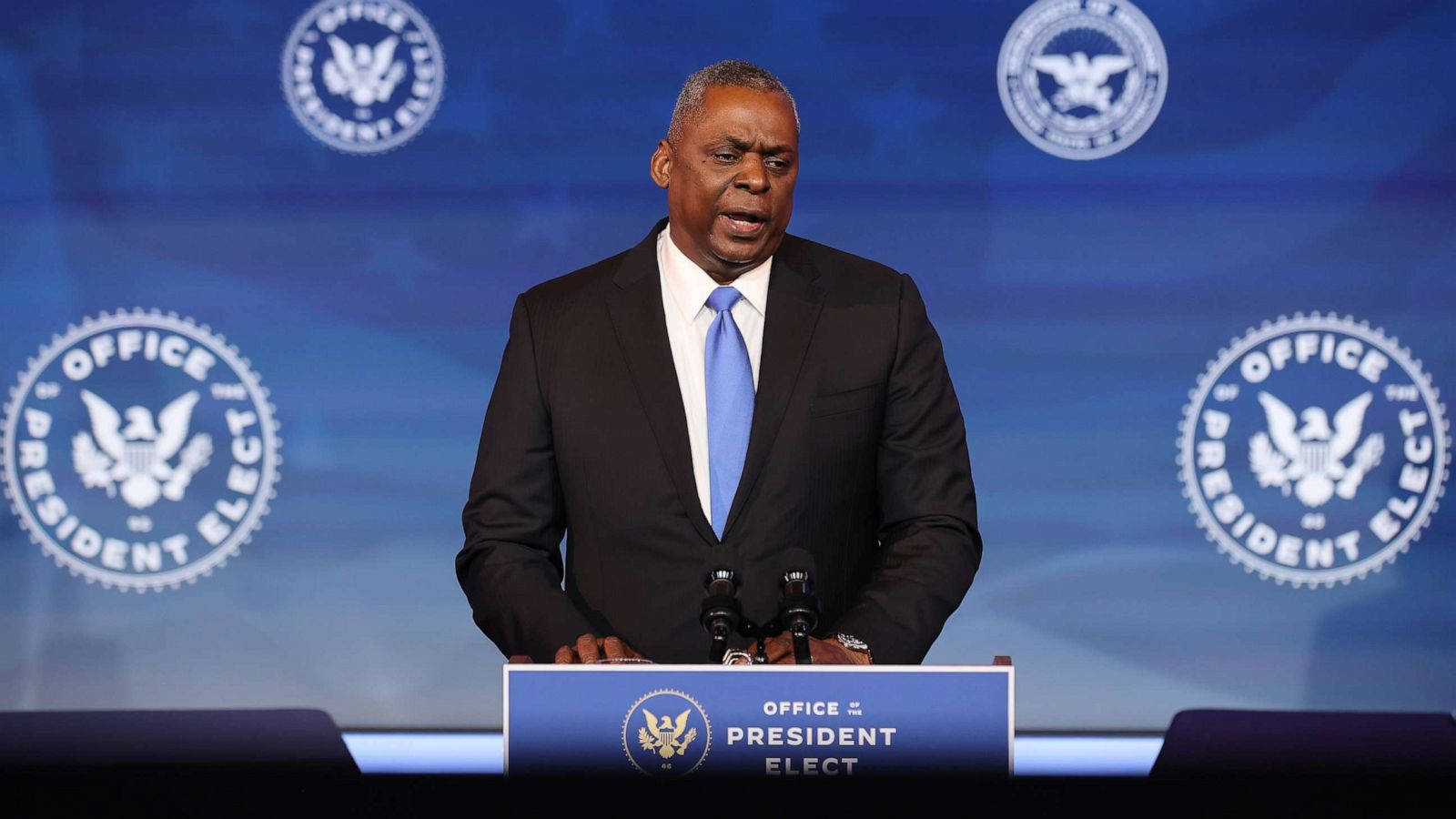 穿西裝的男子在帶有官方印章的President Elect講台上發言。
