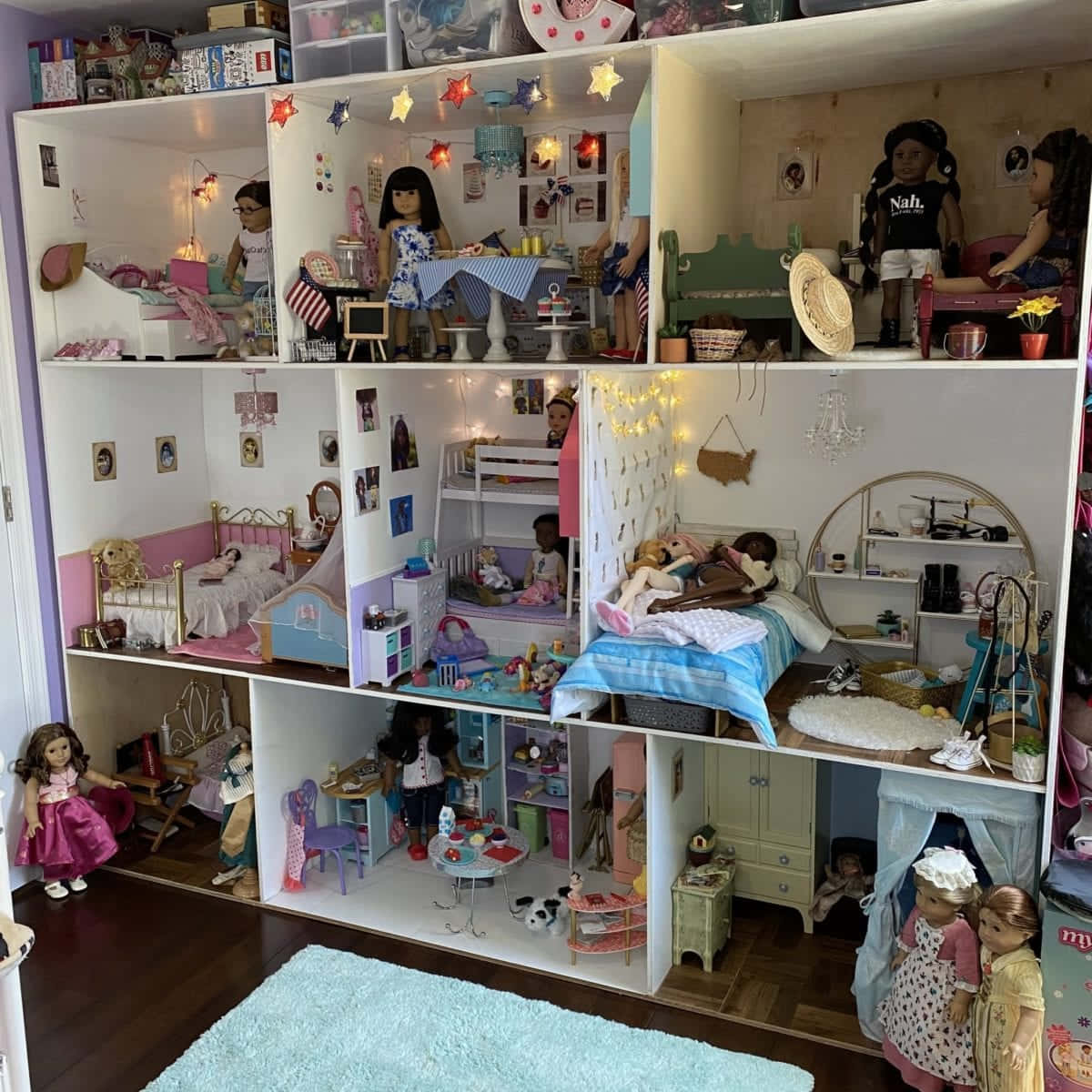 美國女孩享受戶外一日 壁紙 — 一個多層娃娃屋，內有詳細的房間和各種場景中的娃娃，由仙女燈照亮。