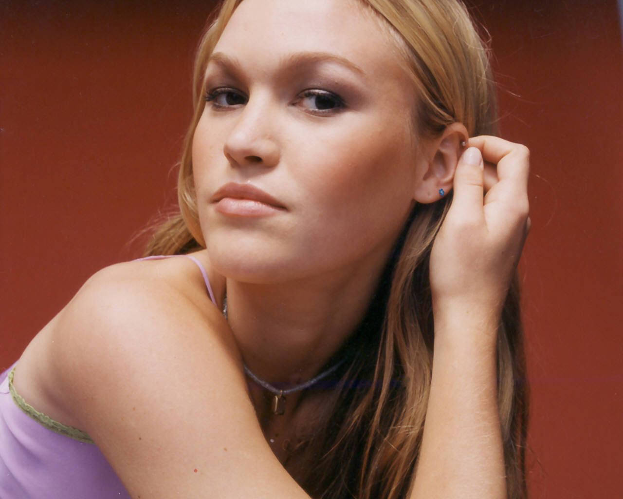 年輕女性穿著紫色上衣在紅色背景上觸碰耳朵。