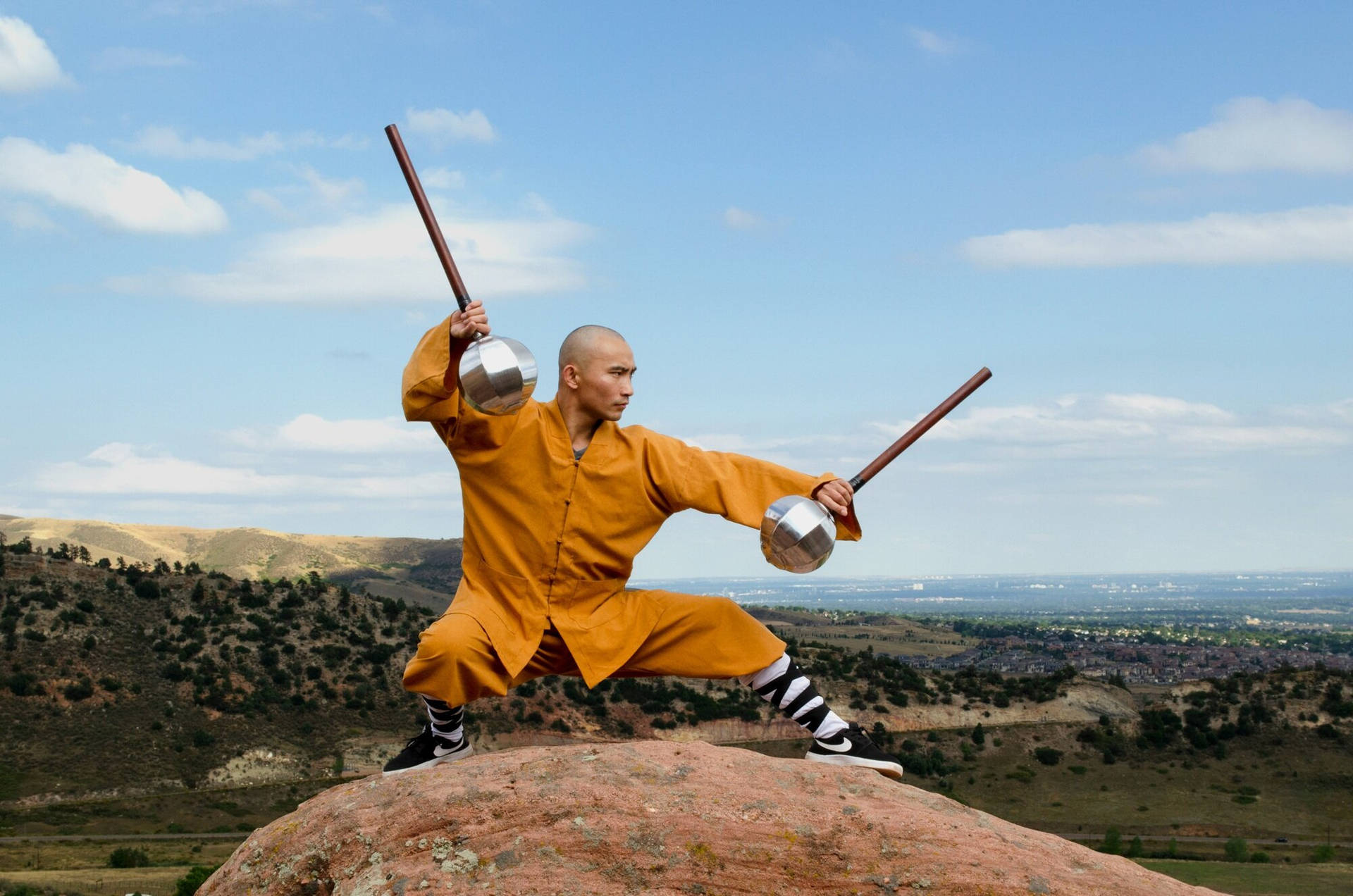 僧侶在山頂上使用加重杖練習武術，俯瞰山谷。