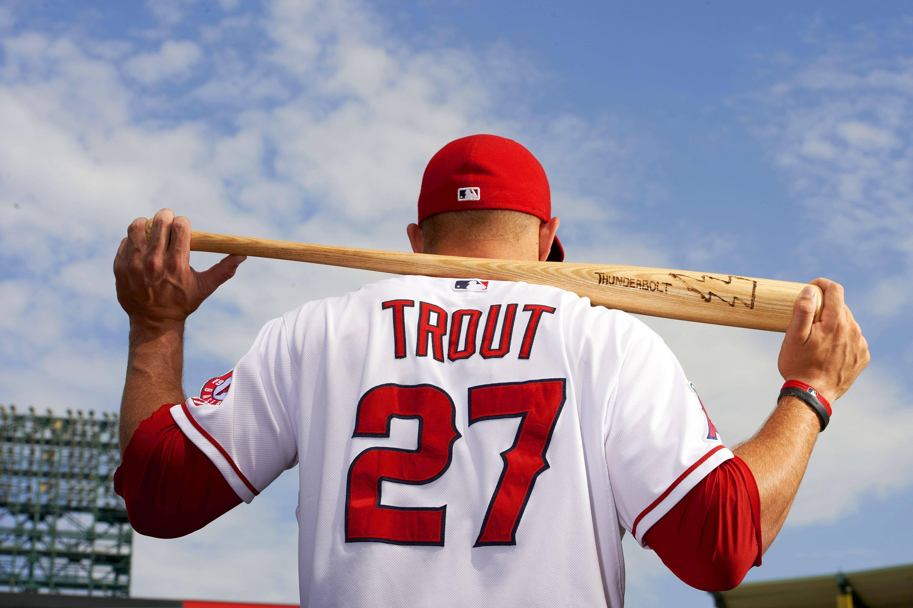美國棒球選手邁克·特勞特 壁紙 — 棒球手 Mike Trout 的背影，他將球棒扛在肩上，背景是晴朗的藍天和零星的白雲。