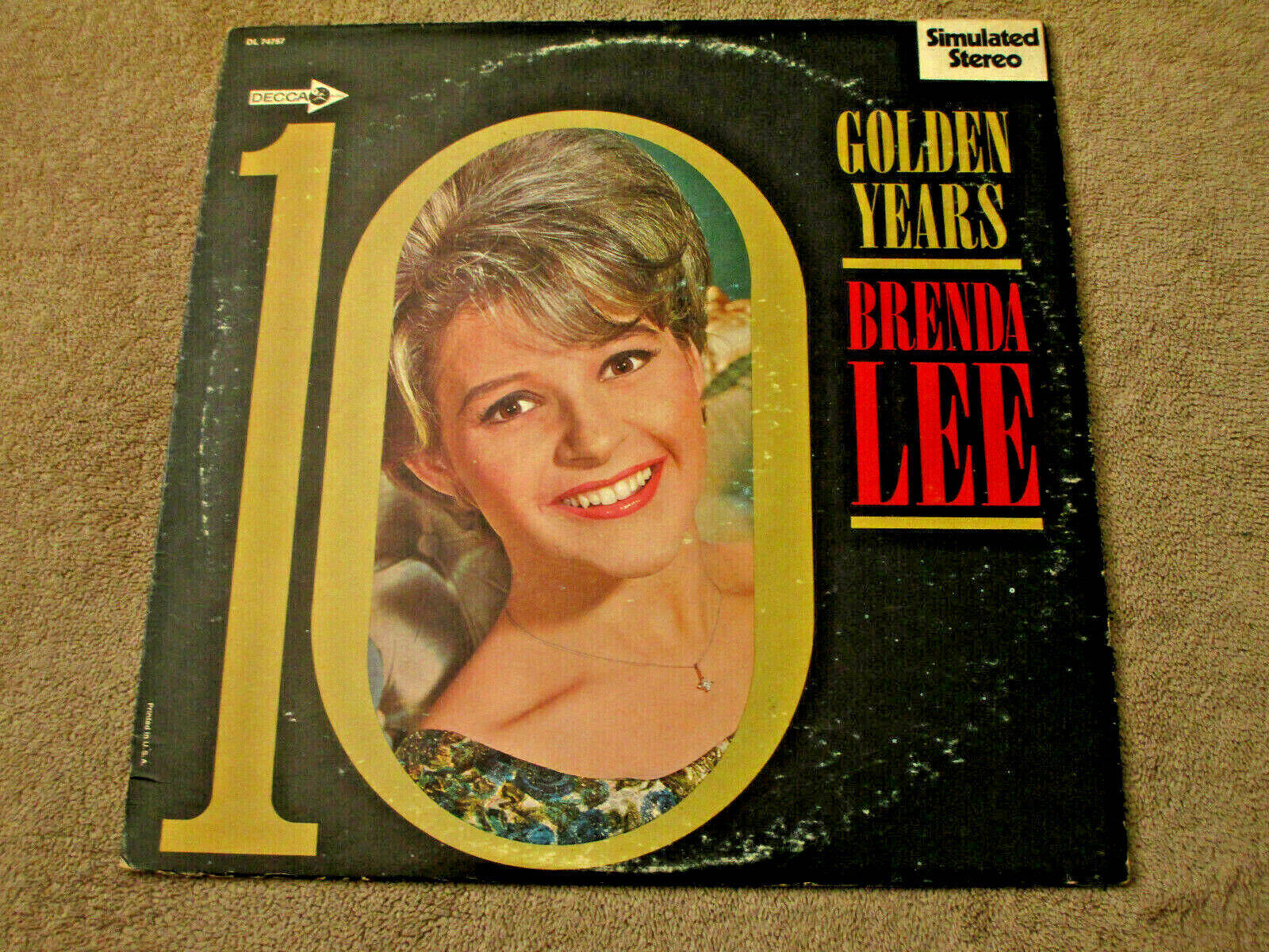 美國歌手Brenda Lee《Golden Years of Brenda Lee》復古黑膠專輯 壁紙 — Brenda Lee《10 Golden Years》的復古黑膠唱片封面，黑色背景上金色數字十內有一個微笑的肖像。