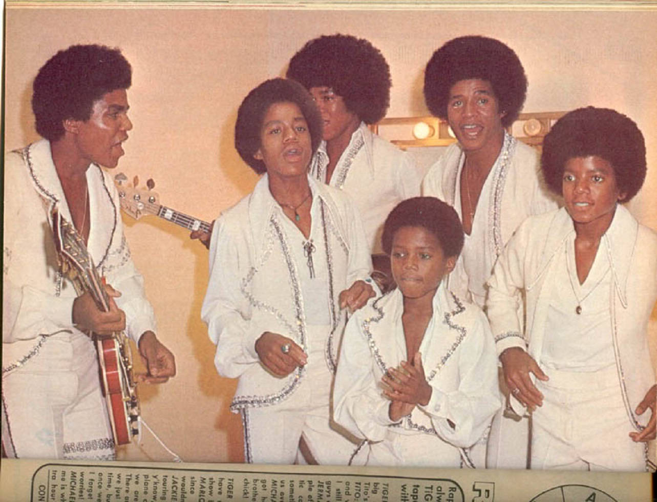 Jackson Five 穿著白色閃片服裝在攝影棚中拿著結他擺姿勢。 — 米高積遜 GIF 壁紙