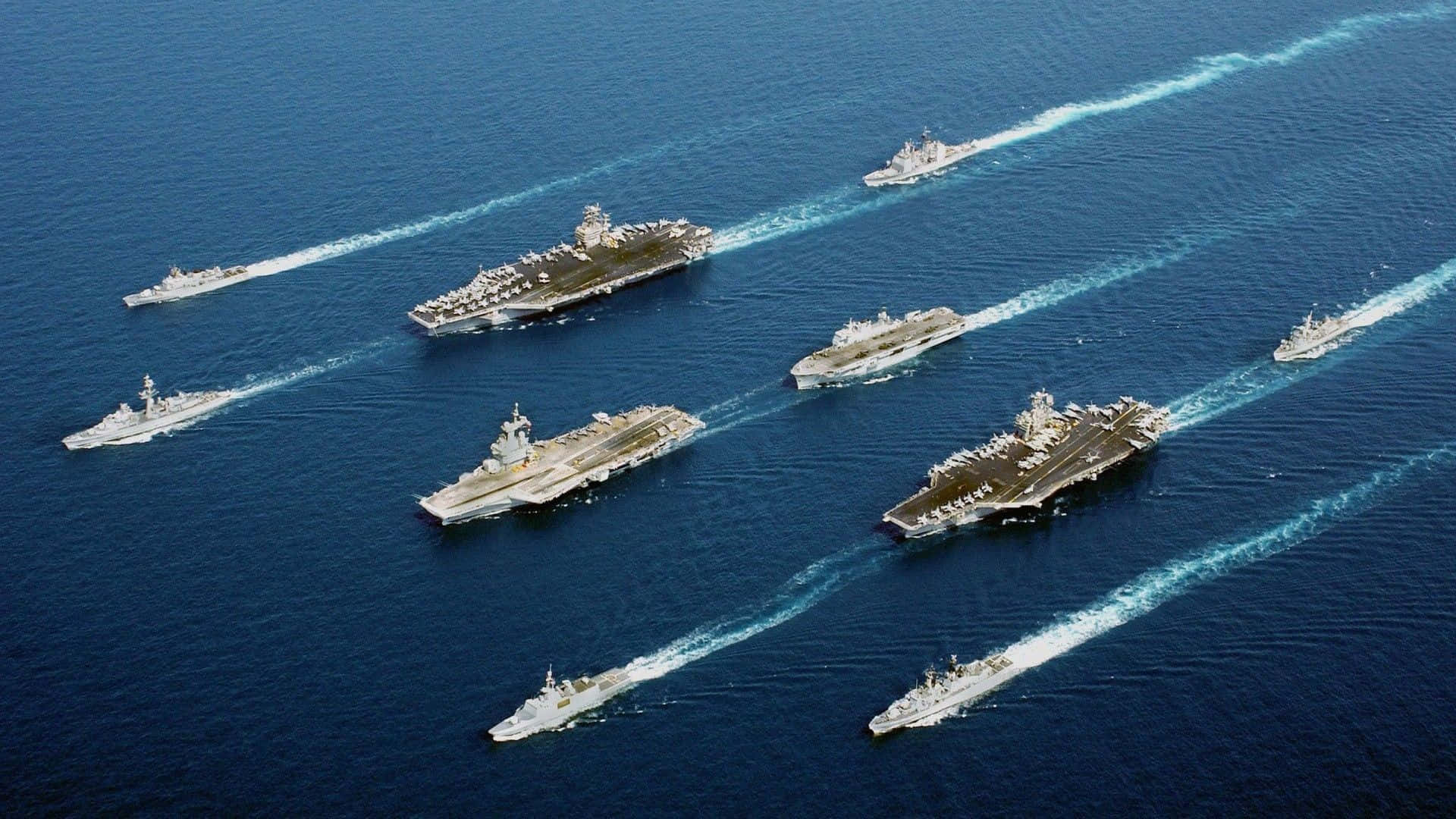 美國海軍戰艦的經典風景 壁紙 — 多艘航空母艦及護航艦在深藍色海洋上編隊航行的鳥瞰圖。